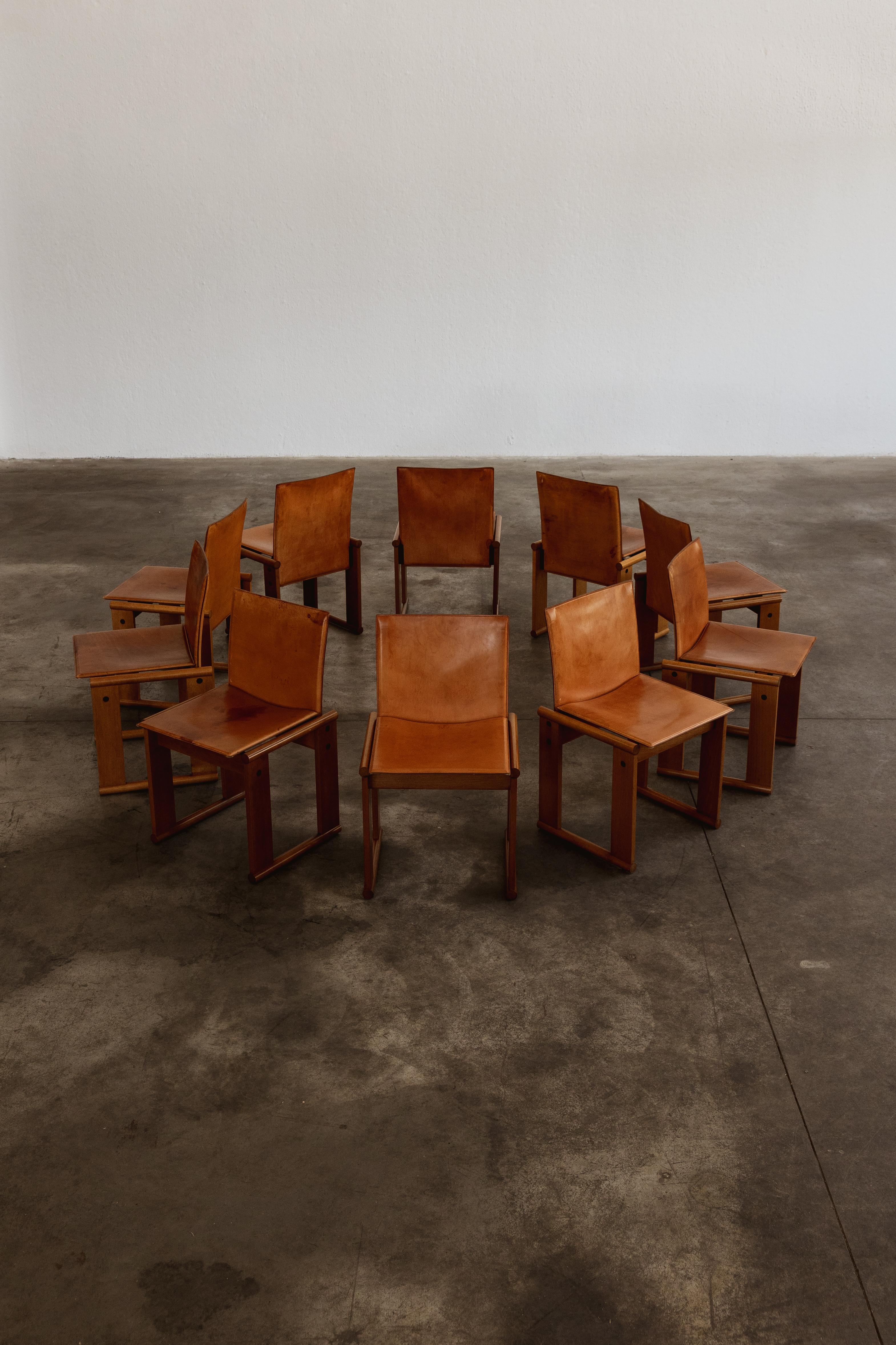 Afra & Tobia Scarpa dining chairs for Molteni, patinated cognac leather and walnut, Italy, 1974, set of ten.

The particular feature of this model is the support structure composed of two equal trestles in solid wood attached to shaped metal tubing,