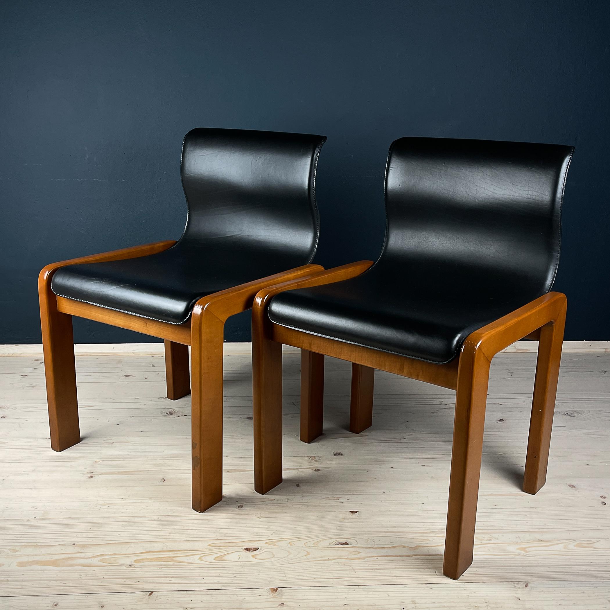 This is a stunning pair of dining chairs, crafted from black leather and brown lacquered wood.
Designed in Italy in 1966 by the award-winning Afra & Tobia Scarpa, these chairs are a unique combination of materials, with the entire seating structure