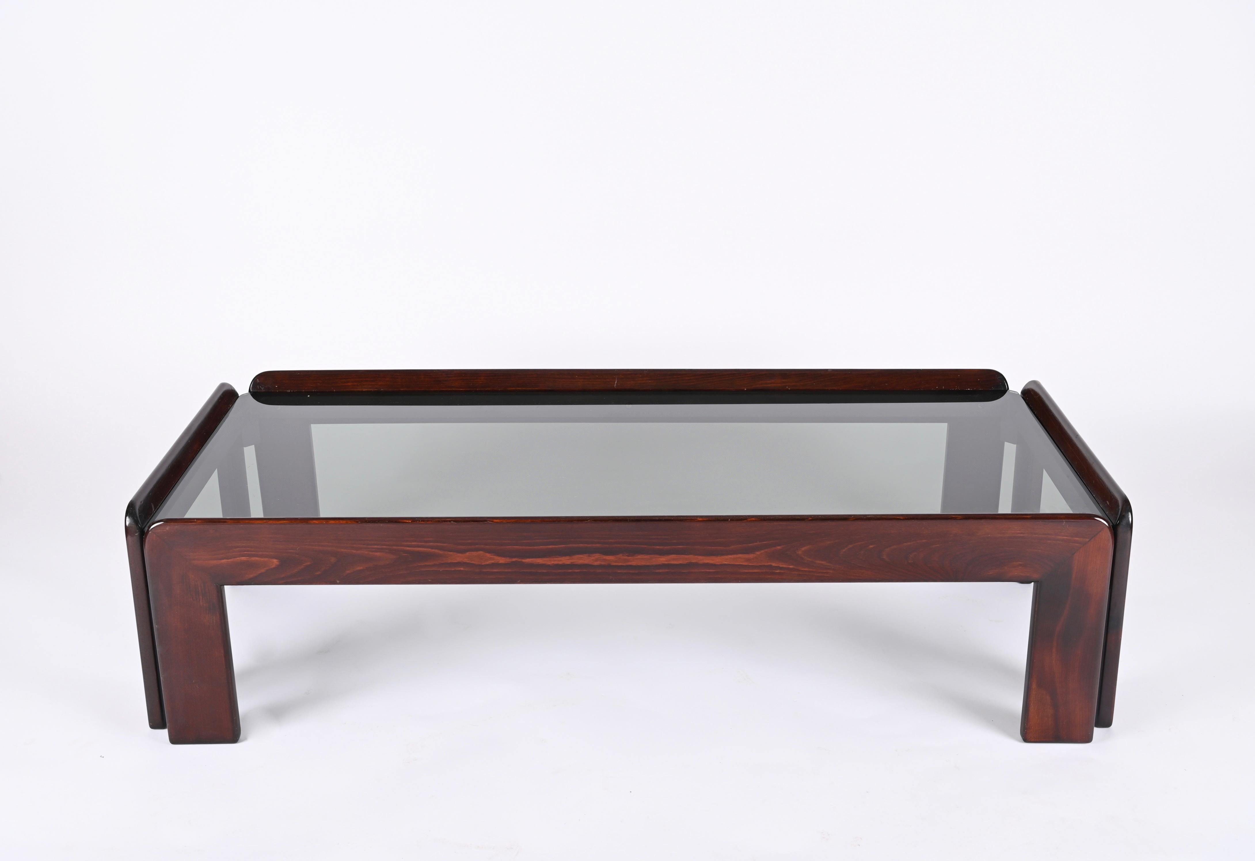 Stunning Midcentury rectangular solid wood coffee table with smoked glass top. It was produced in Italy in the 1960s by Cassina and designed by Afra & Tobia Scarpa. The wood structure is reinforced internally by a rectangular black metal frame that