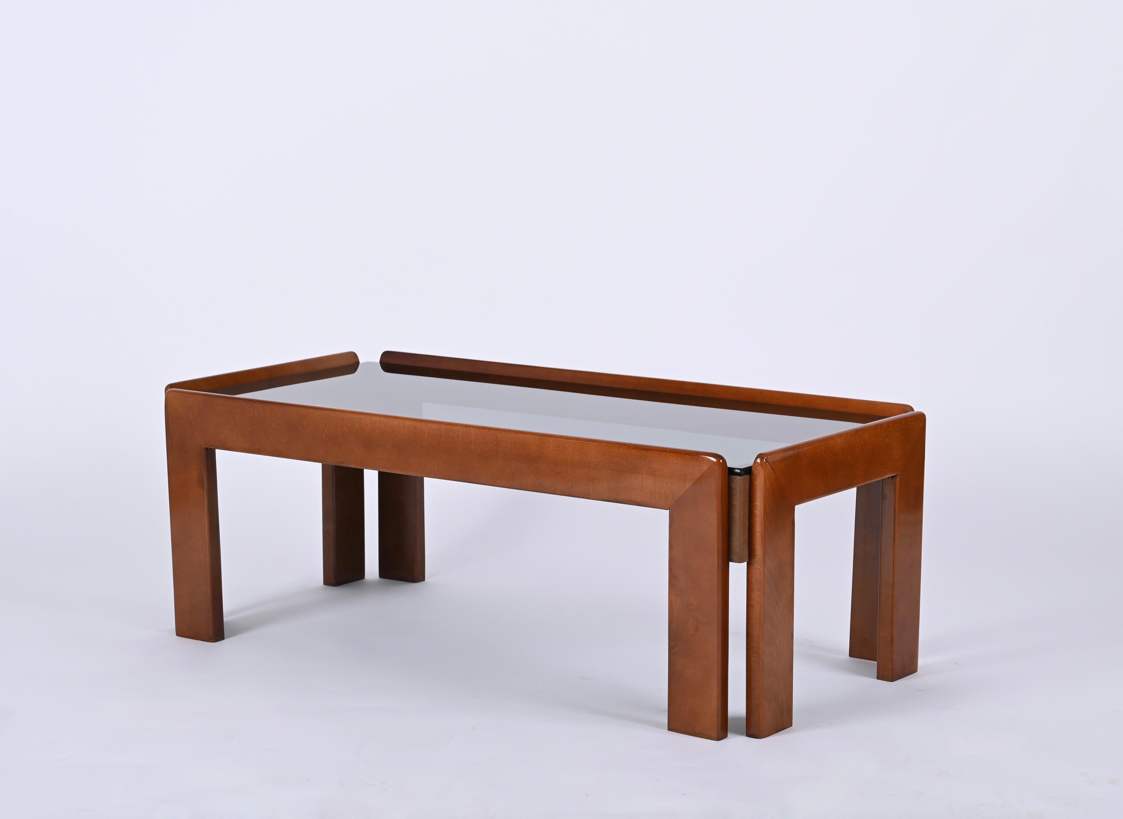 Stunning midcentury rectangular solid wood coffee table with smoked glass top. It was produced in Italy in the 1960s by Cassina and designed by Afra & Tobia Scarpa.

The coffee table is made in a beatiful yet sturdy walnut wood and is in amazing