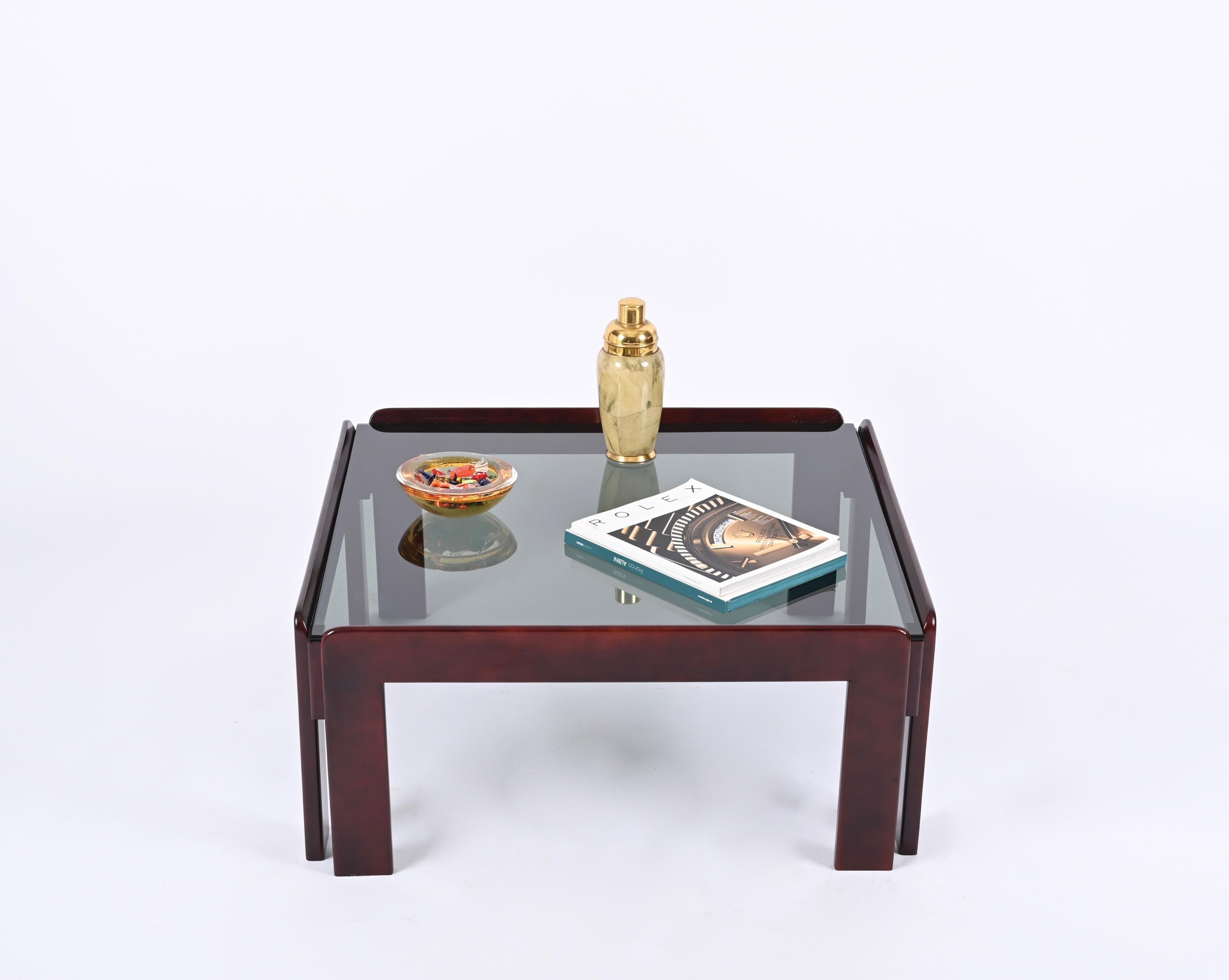 Gorgeous mid-century square coffee table in dark walnut with smoked glass top. It was produced in Italy in the 1960s by Cassina and designed by Afra & Tobia Scarpa.

You are going to love the clean lines and the presence of the dark-toned, smoked