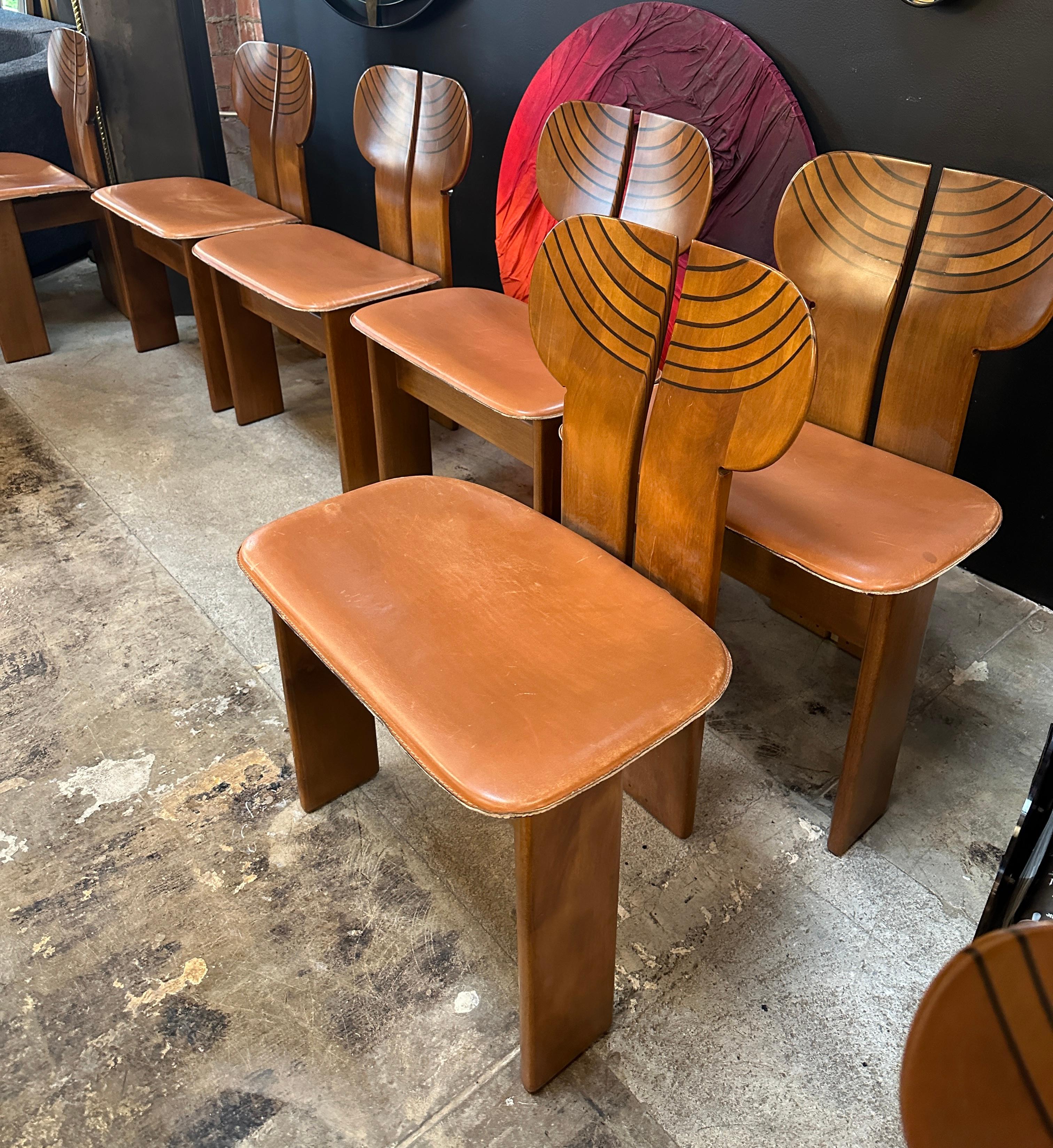 These chairs are an exquisite design by Afra and Tobia Scarpa for Maxalto, showcasing the duo's signature blend of form, function, and craftsmanship. The unique split-backrest design with decorative, curved inlays creates a visually striking effect