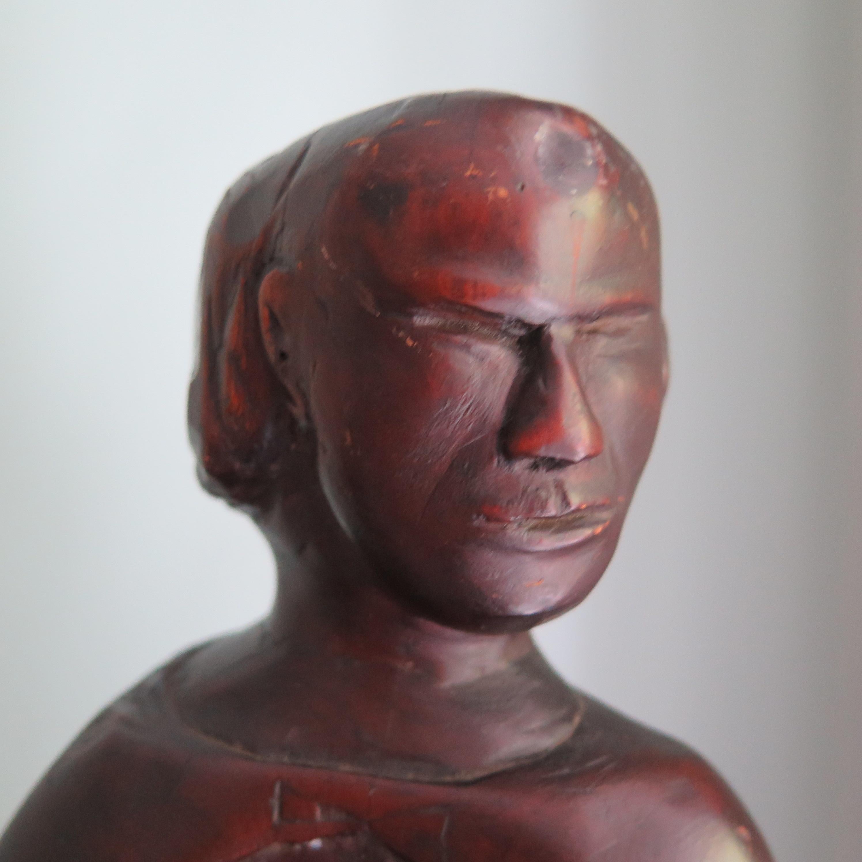 Folk sculpture of a carved wood nude with mask-like face. The turned body is made more dramatic by the draped cape and the surface with patina of age.