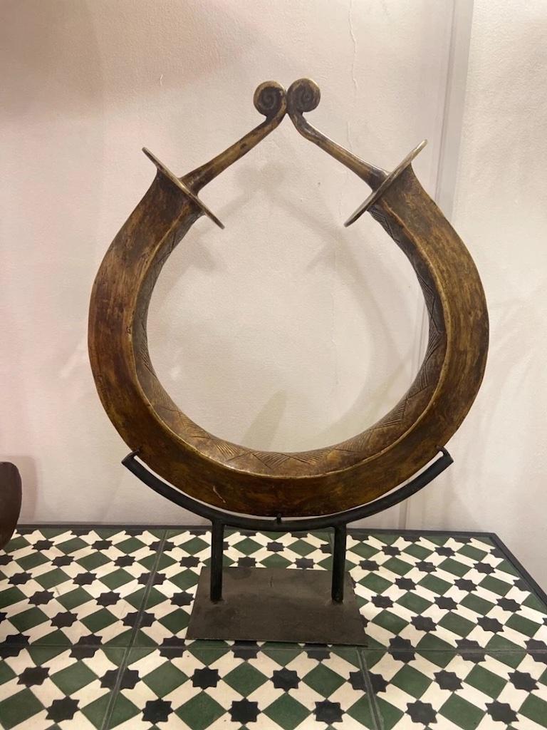 A beautiful curved bronze patina'd African currency piece on a stand.

This currency from Yoruba, Nigeria is now a stunning decorative ornament or collectors item. 

Often referred to as a 