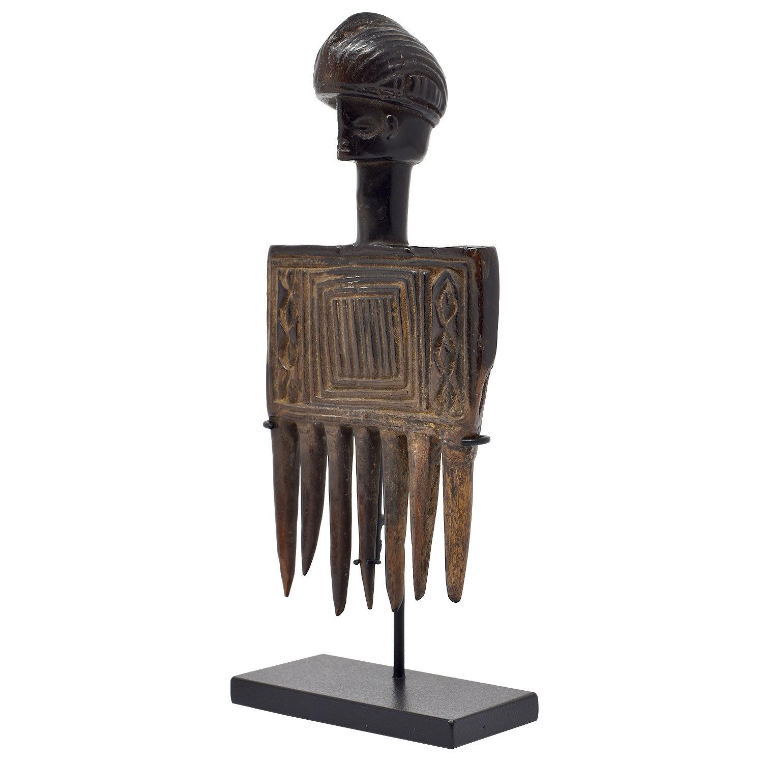 Early 20th Century African Antique Wood Comb with Human Head

From the Chokwe Culture of Angola. A fine, old, much used comb with a glossy, glasslike patina. Of traditional form with a human head with a  precise coiffure on an elongated neck for the