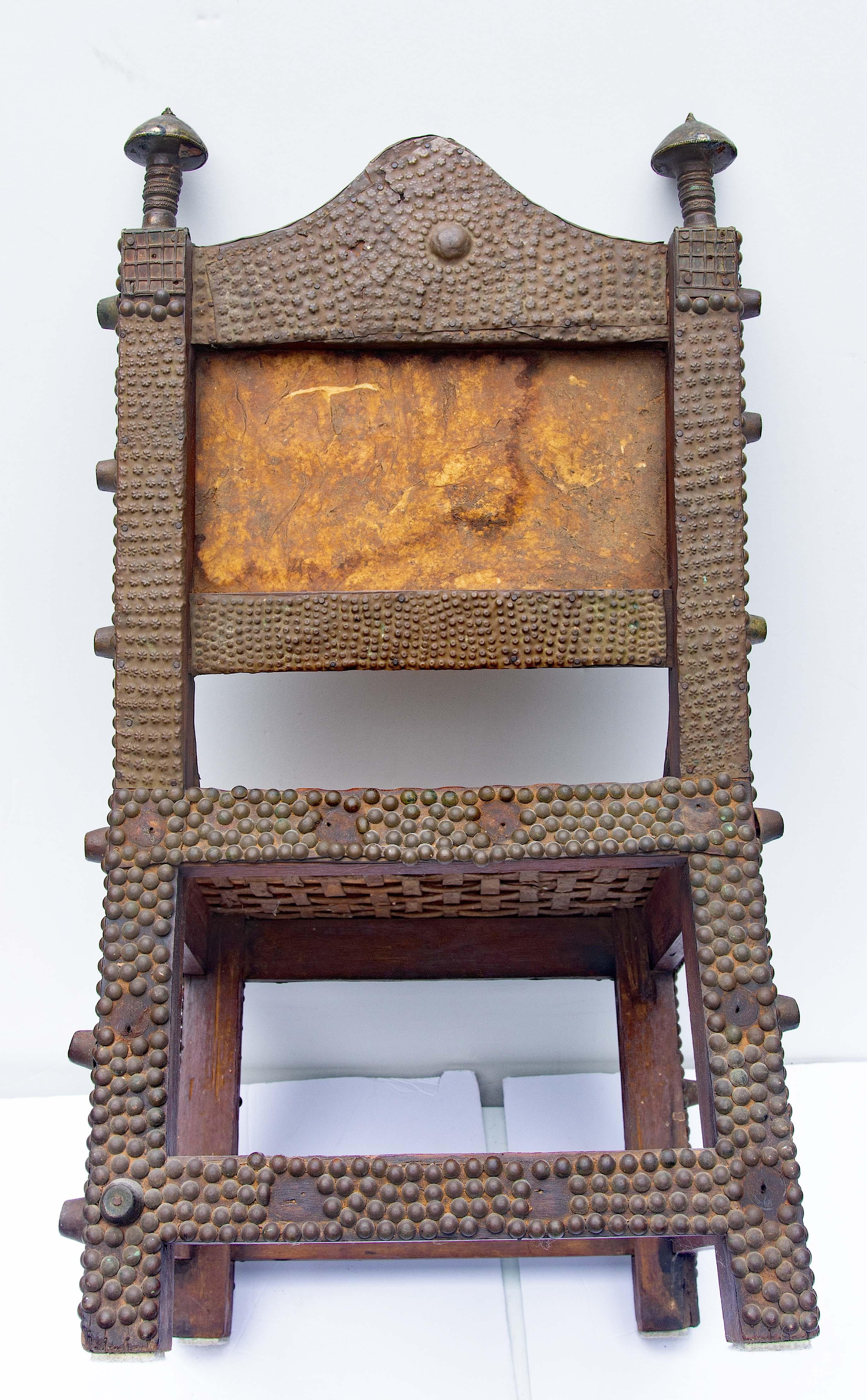 African Ashanti tribe chiefs chair. Highly decorated with brass tacks and pressed brass decorations. Hardwood with vellum back and seat. Ghana. Late 19th century.