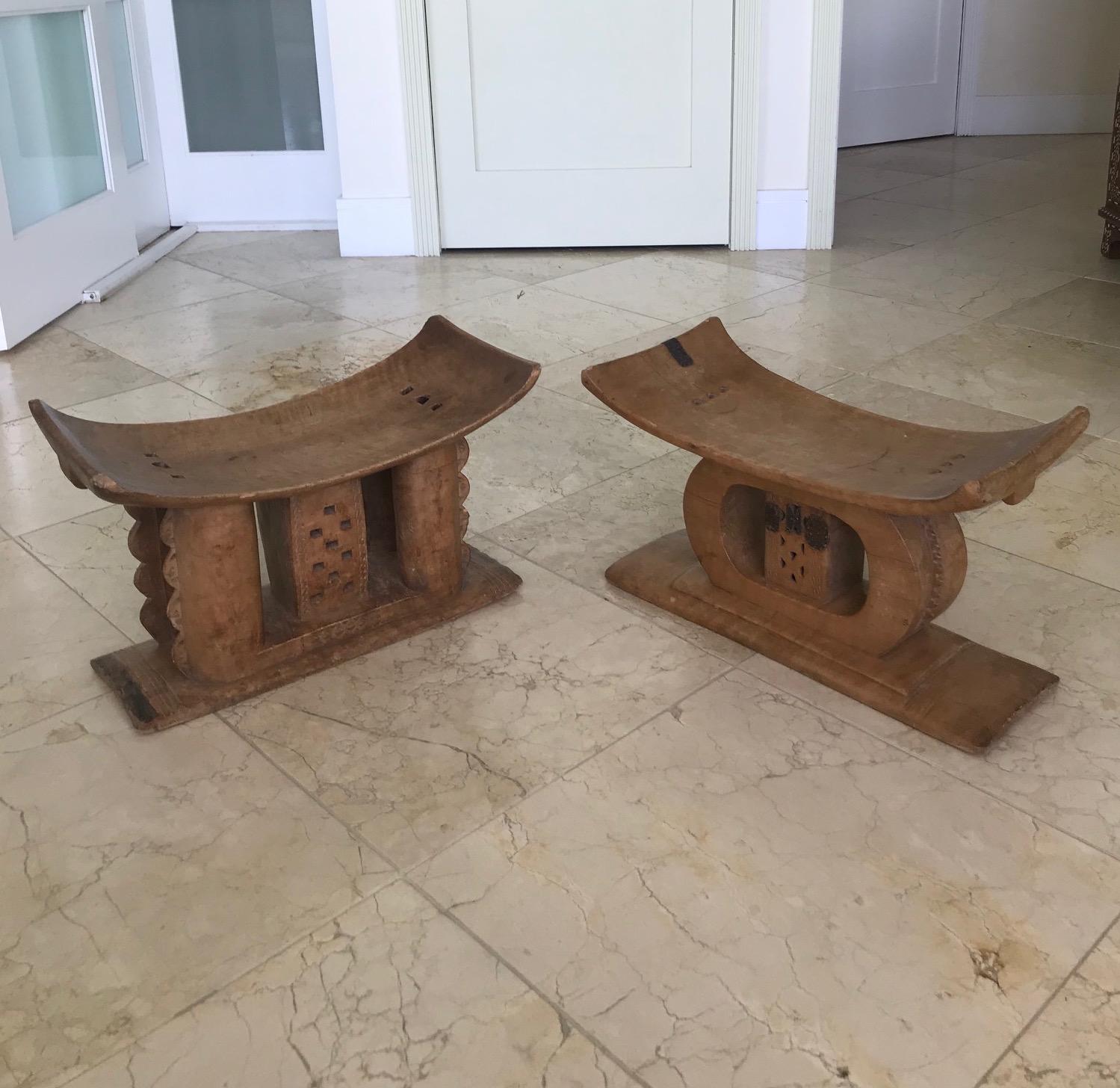 Genuine traditional African Ashanti stools signifying power and status, and symbols of leadership. Carved from a single block of wood featuring curved seat and intricate support base. The stools feature a series of incised tribal carvings, hand
