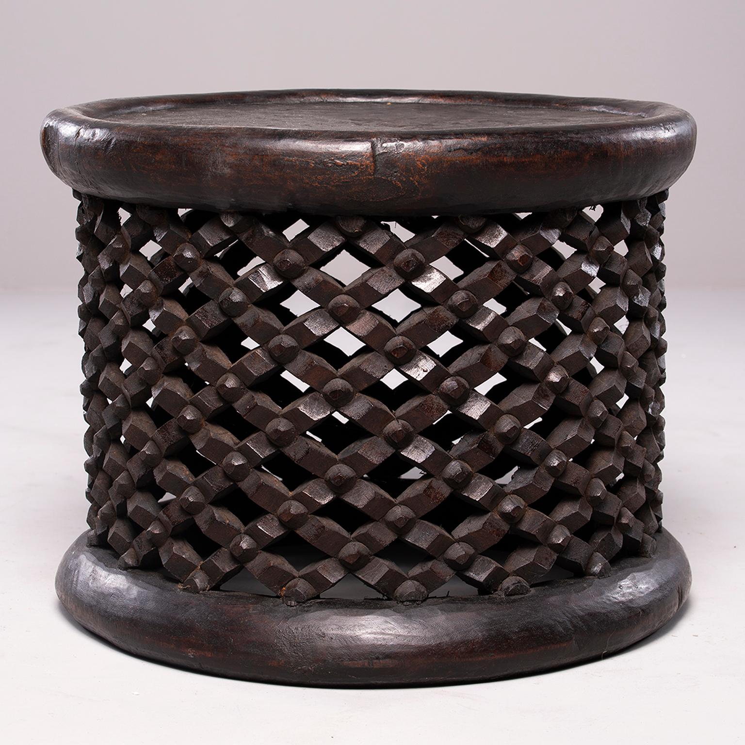 Handmade wood table from Cameroon is dark stained wood with round table top and carved lattice/grid pattern. Can be used as a side table or stool. Other similar pieces with variations in size/design available at the time of this posting.