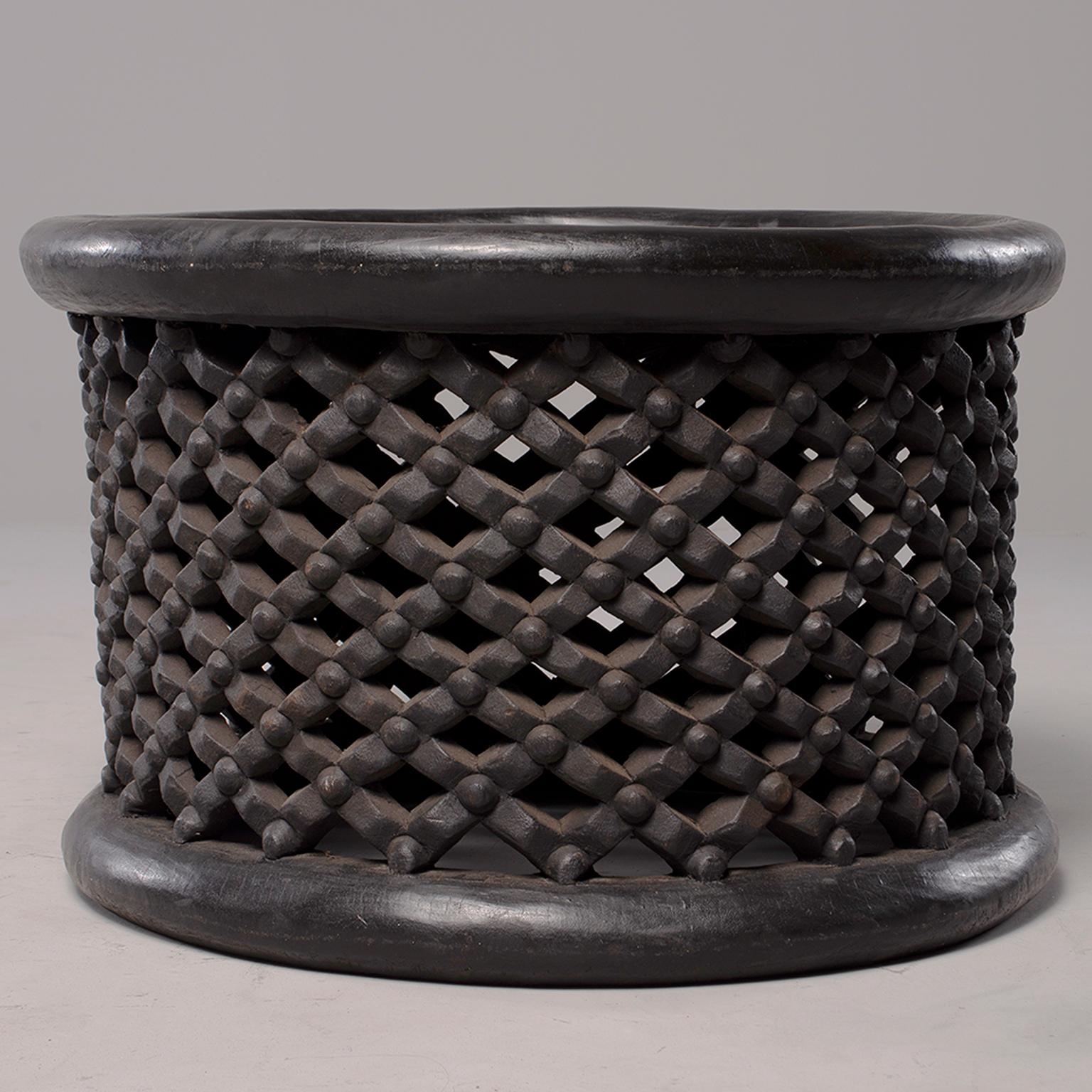 Round table or stool from Bamileke people in Cameroon is made of dark stained carved wood with an open work grid with knobs pattern, circa 1980s.
 