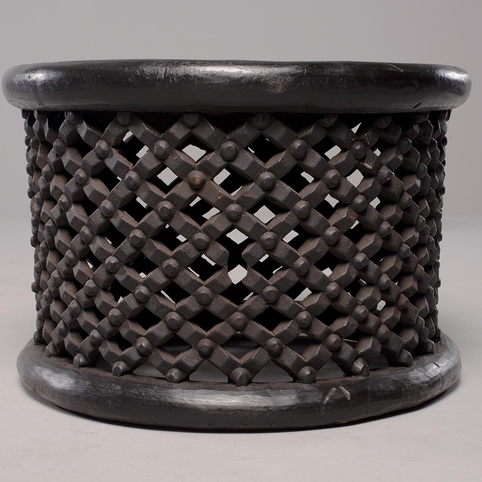 Round table or stool from Bamileke people in Cameroon is made of dark stained carved wood with an open work grid and knobs pattern, circa 1980s. The size and height is suitable to use for a stool or side / occasional table.
       