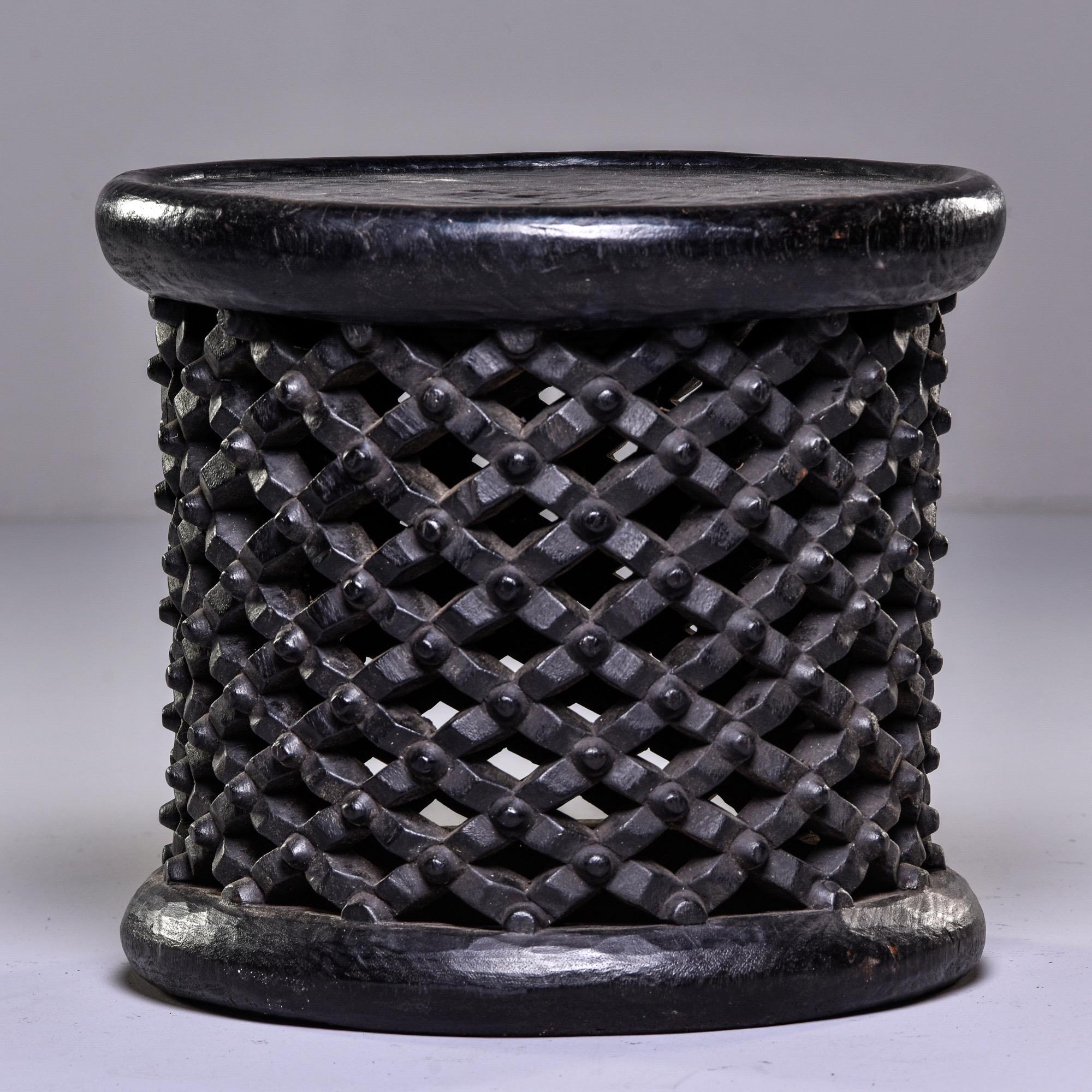 Round dark wood stool or side table, circa 1980s. Hand carved by a artist in Cameroon, this style is known as a spider stool because of its knobby web-like base. The Bamileke people see spiders as a link between the living and the dead and use