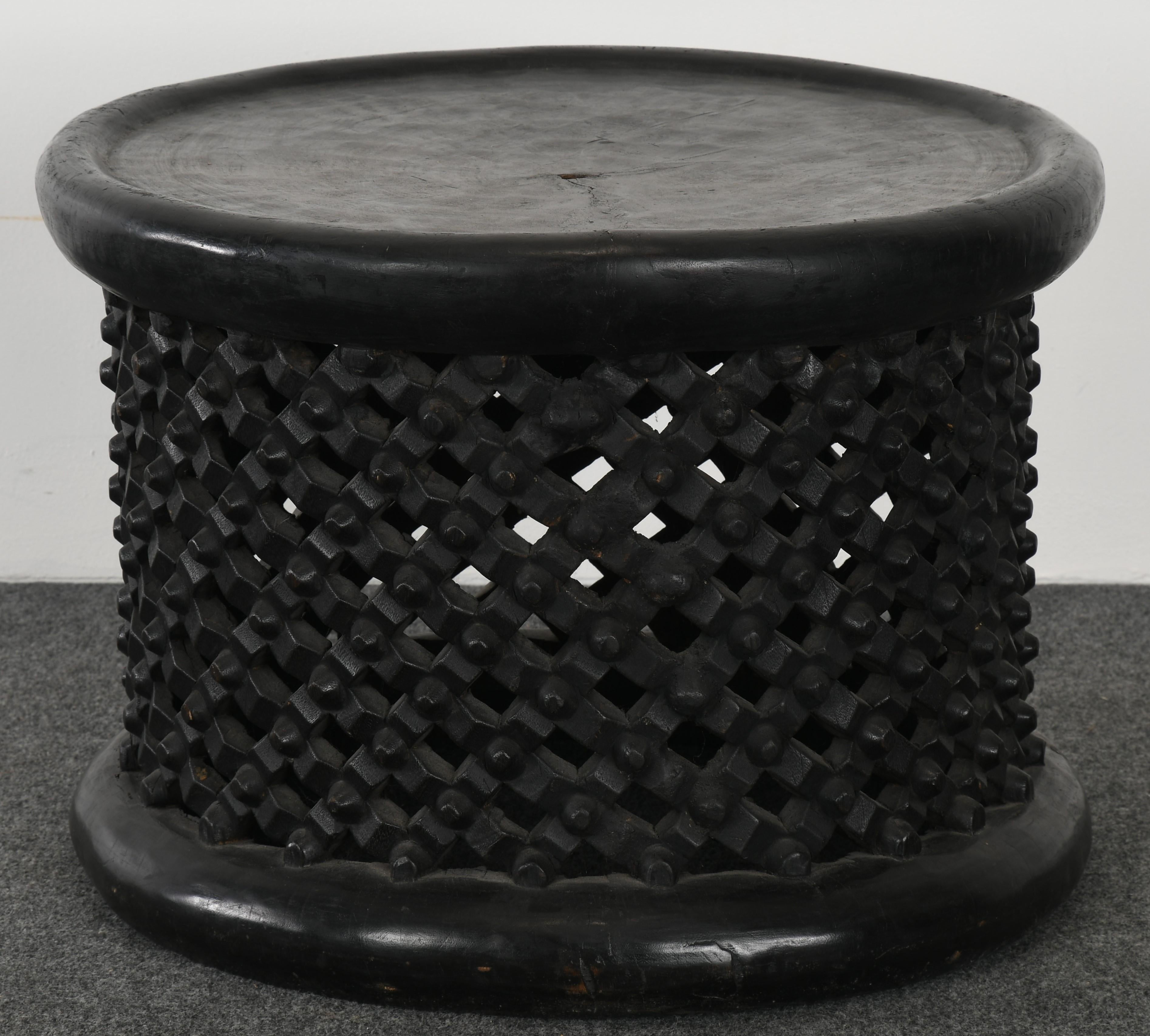 A Cameroon wood drum table with pierced and carved lattice base. The size and height is great to use as a stool, side table, or occasional table. The lattice work on the bench is in good condition, however, due to the inherent nature of solid wood