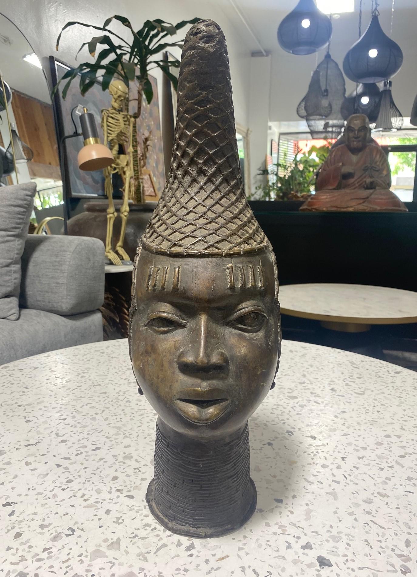 Magnifique buste/tête en bronze de taille relativement importante représentant Idia, la première reine mère du royaume du Bénin (dans l'actuel Nigeria) au XVIe siècle.  Traditionnellement, le rôle de dirigeant était réservé à l'Oba ou roi mâle.  Les