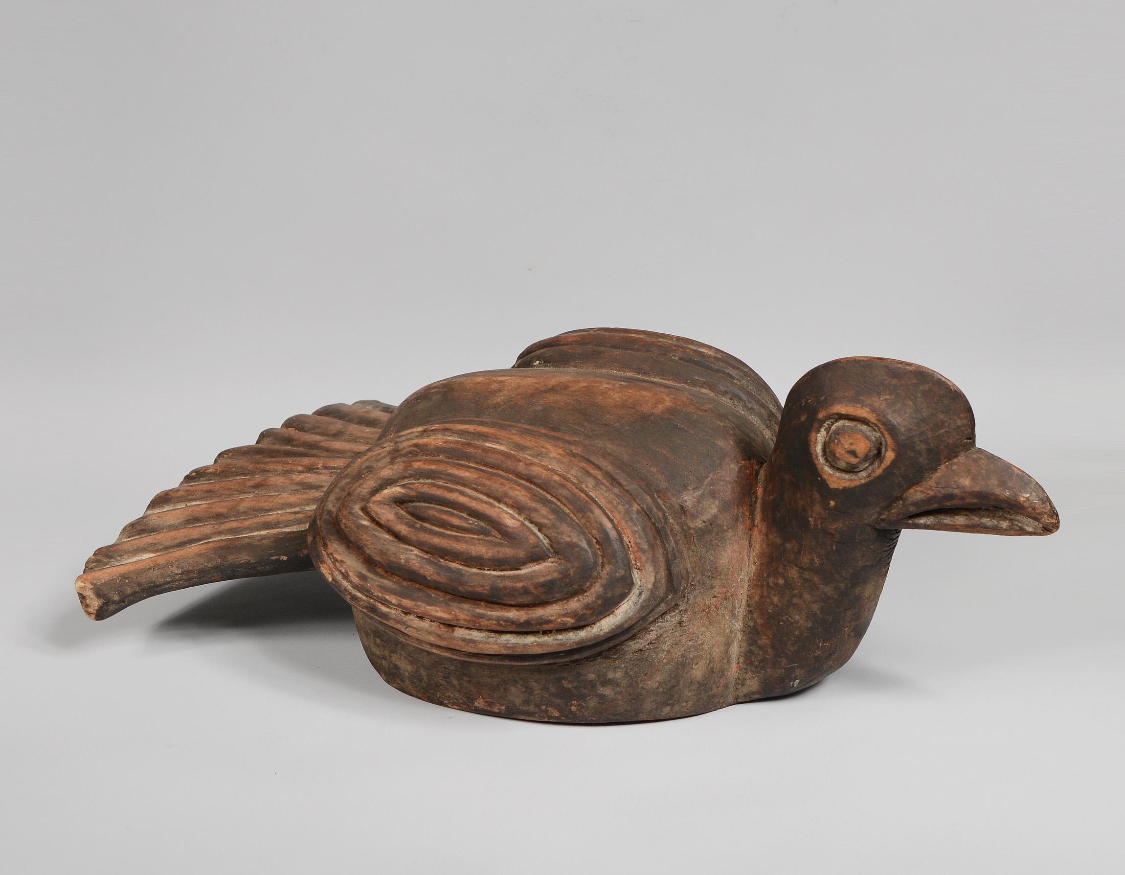 Carved wood and pigment bird form headdress from the Bamileke of Cameroon. This shows wear. There is some pigment loss and a more recent crack on the bottom edge.