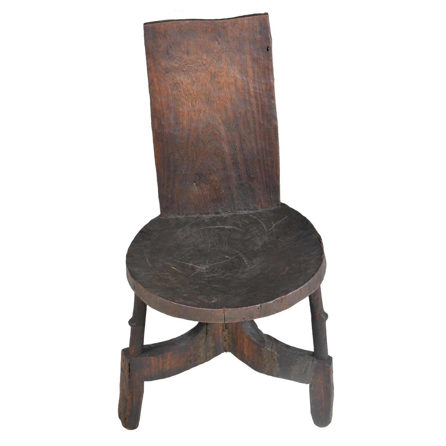 An early 20th century African chieftain chair from the Oromo people in the eastern part of Ethiopia. The Oromo chairs and seats are all identifiable by their distinctive style, with three outwardly curved round legs, a round carved seat and a high