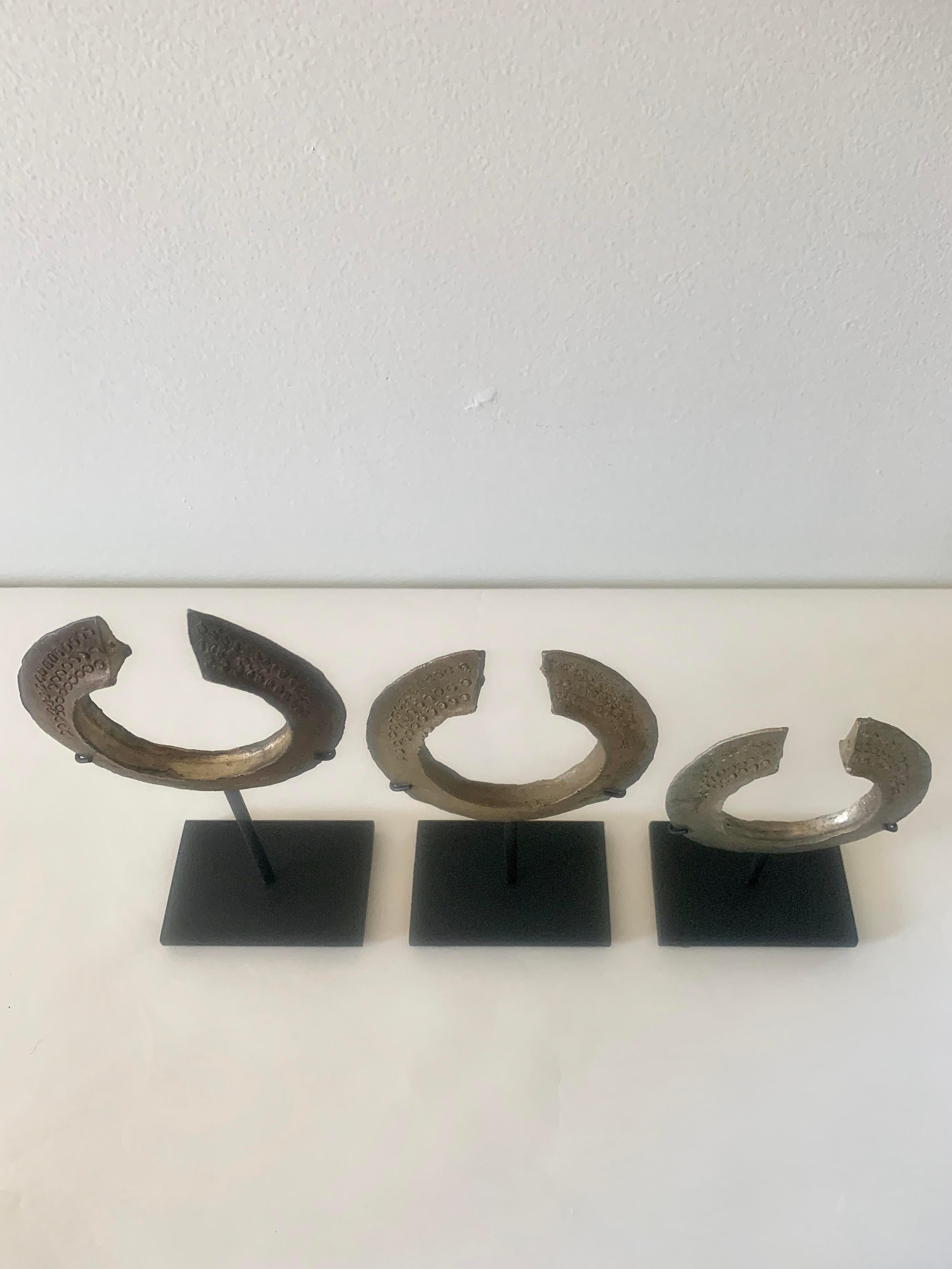 A set of three African currency bracelets on custom black steel stands. Bracelets alone measure 3.5