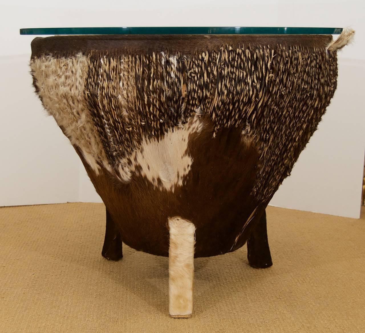 African hide drum table with glass top. Split to hide on one side. Mid-20th century.
