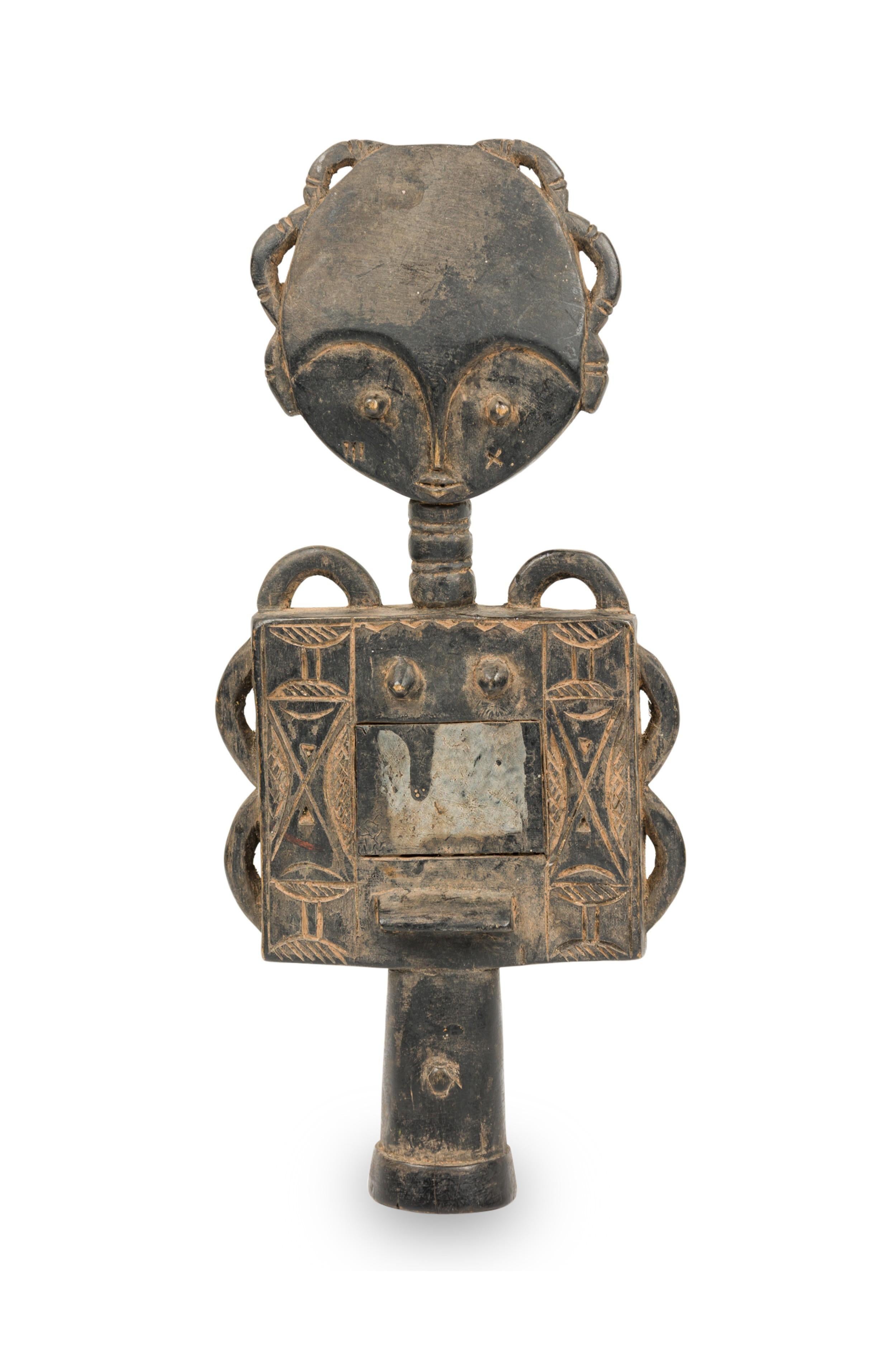 Von den Ashanti handgeschnitzte ghanaische Fruchtbarkeitspuppe aus dem 20. Jahrhundert, die eine Figur mit übertriebenen Augenbrauen, schlangenförmigen Formen über Kopf und Oberkörper und einem gespiegelten Unterleib, umgeben von geschnitzten