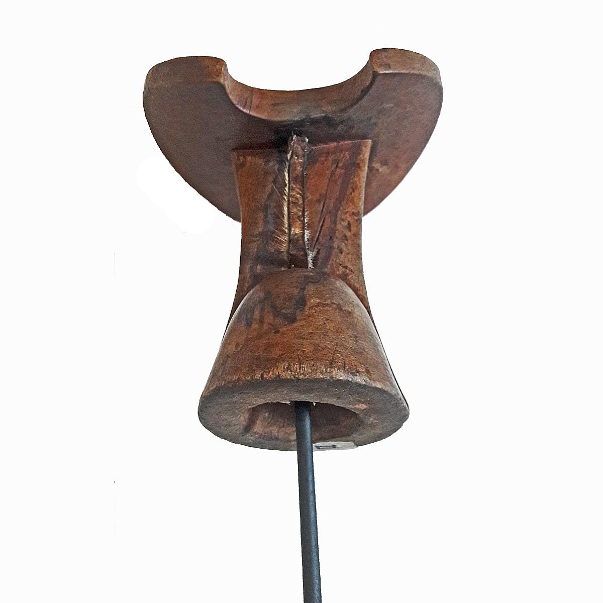 A headrest or stool, hand carved out of a single piece of teak wood, and decorated with traditional carvings, with a braided leather handle. From Ethiopia, late 20th century. Mounted on a black metal stand.