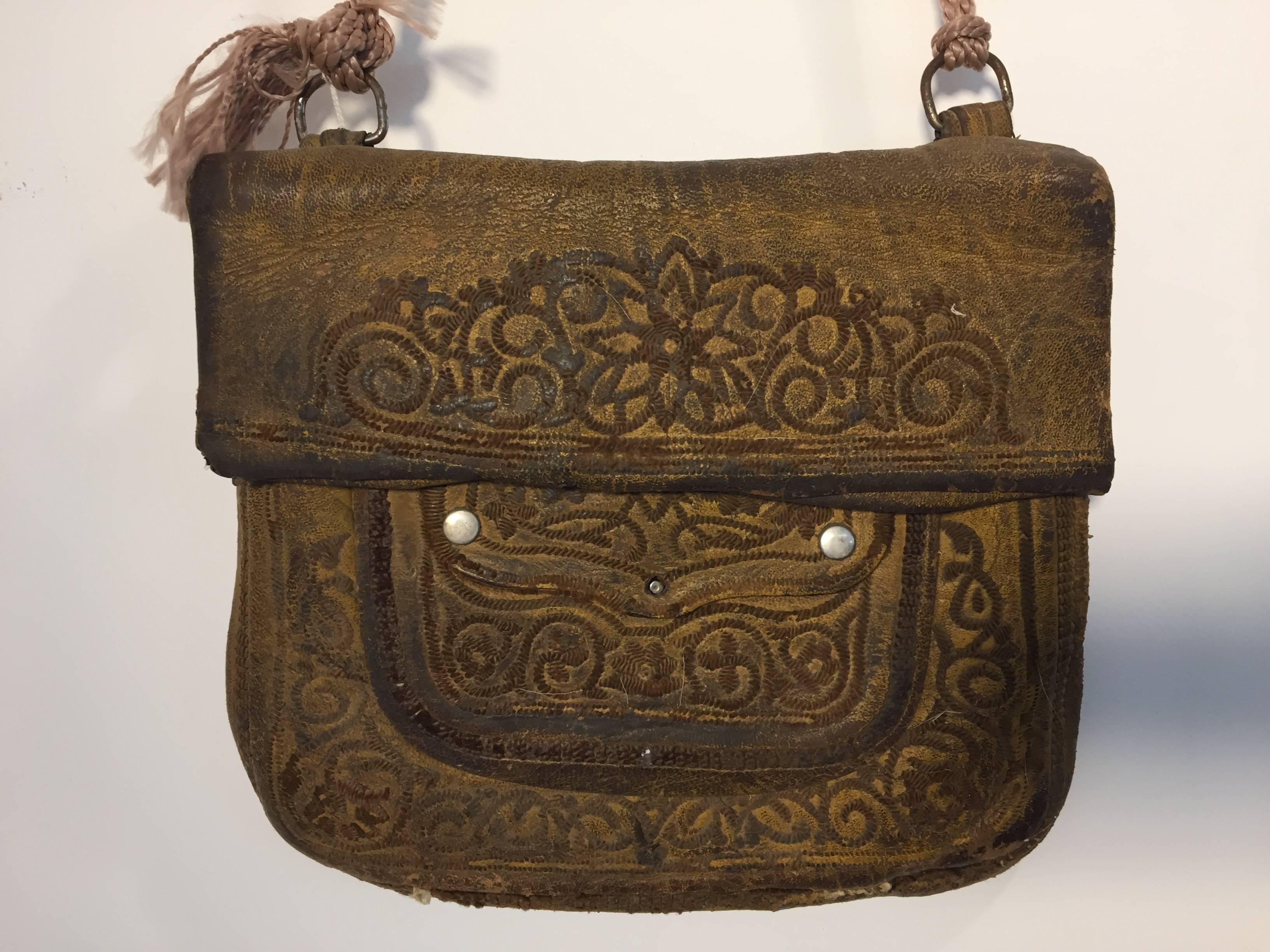 Old leather African Moroccan satchel bag with flap decorated with tribal embroideries.
Hand-tooled in Marrakech, this is an old antique shoulder slim bag, merchants in Morocco when travelling used this bag under their coat to put their money and