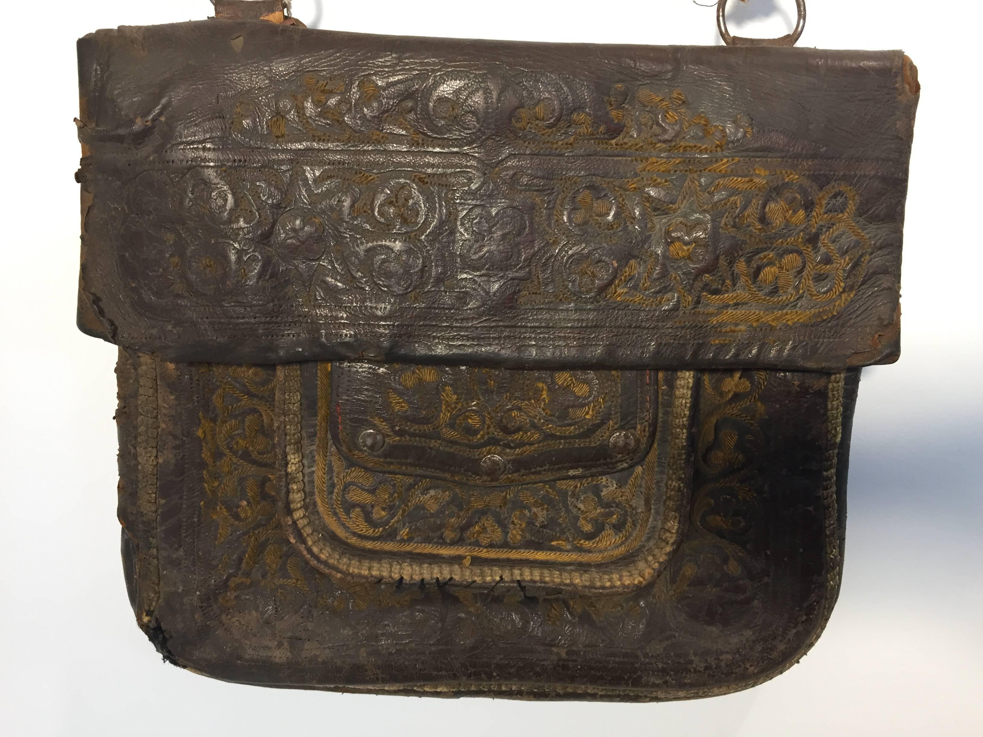 Antique  leather African Moroccan satchel bag with flap decorated with tribal embroideries.
Hand-tooled in Marrakech, this is an old antique shoulder slim bag, merchants in Morocco when traveling used this bag under their coat to put their money and