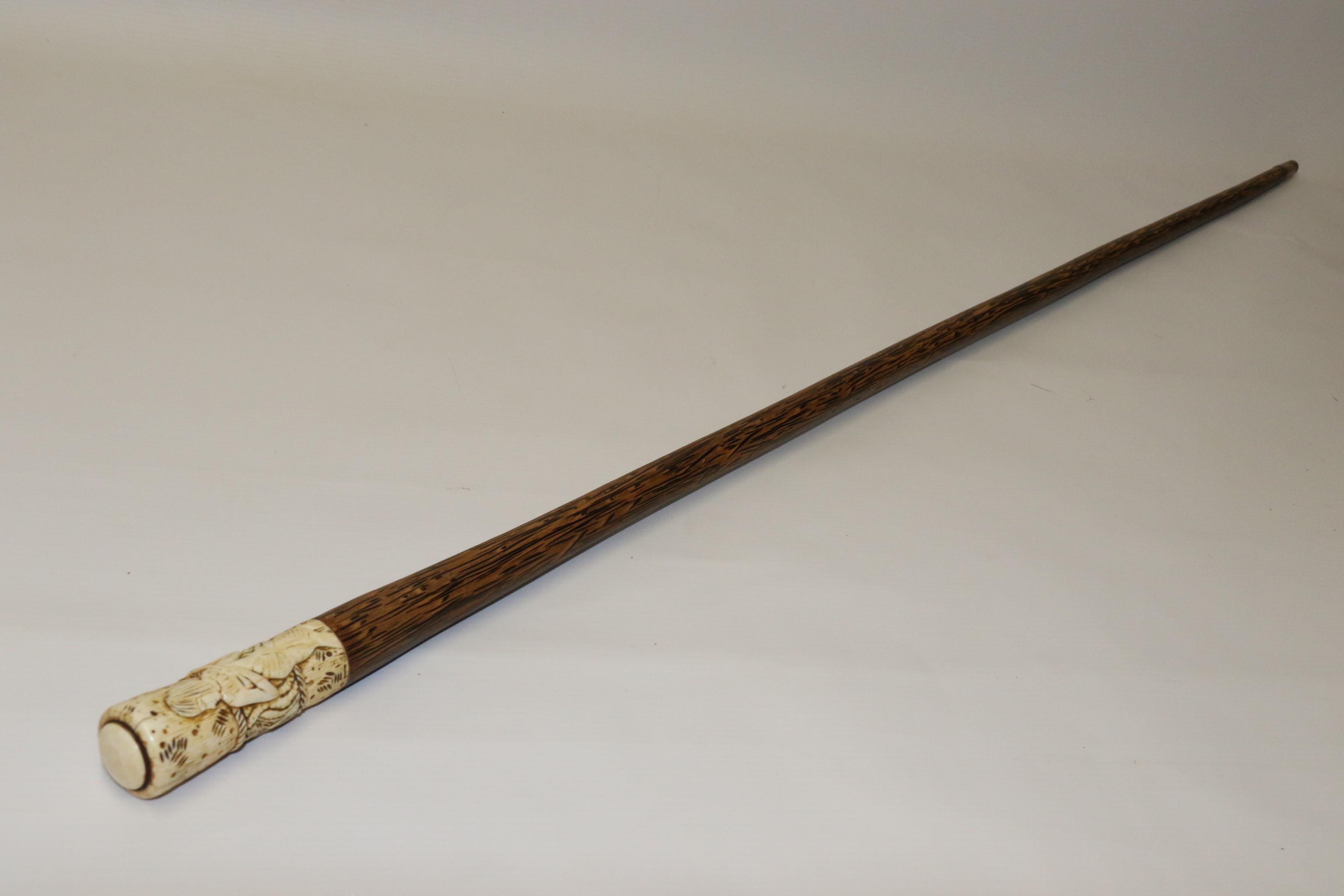 This unusual walking stick dates to the early 20th century and is made from a dense exotic hardwood similar in weight to ebony with a pronounced lighter feathery grain. The handle is made from carved bone with a single female native figure set
