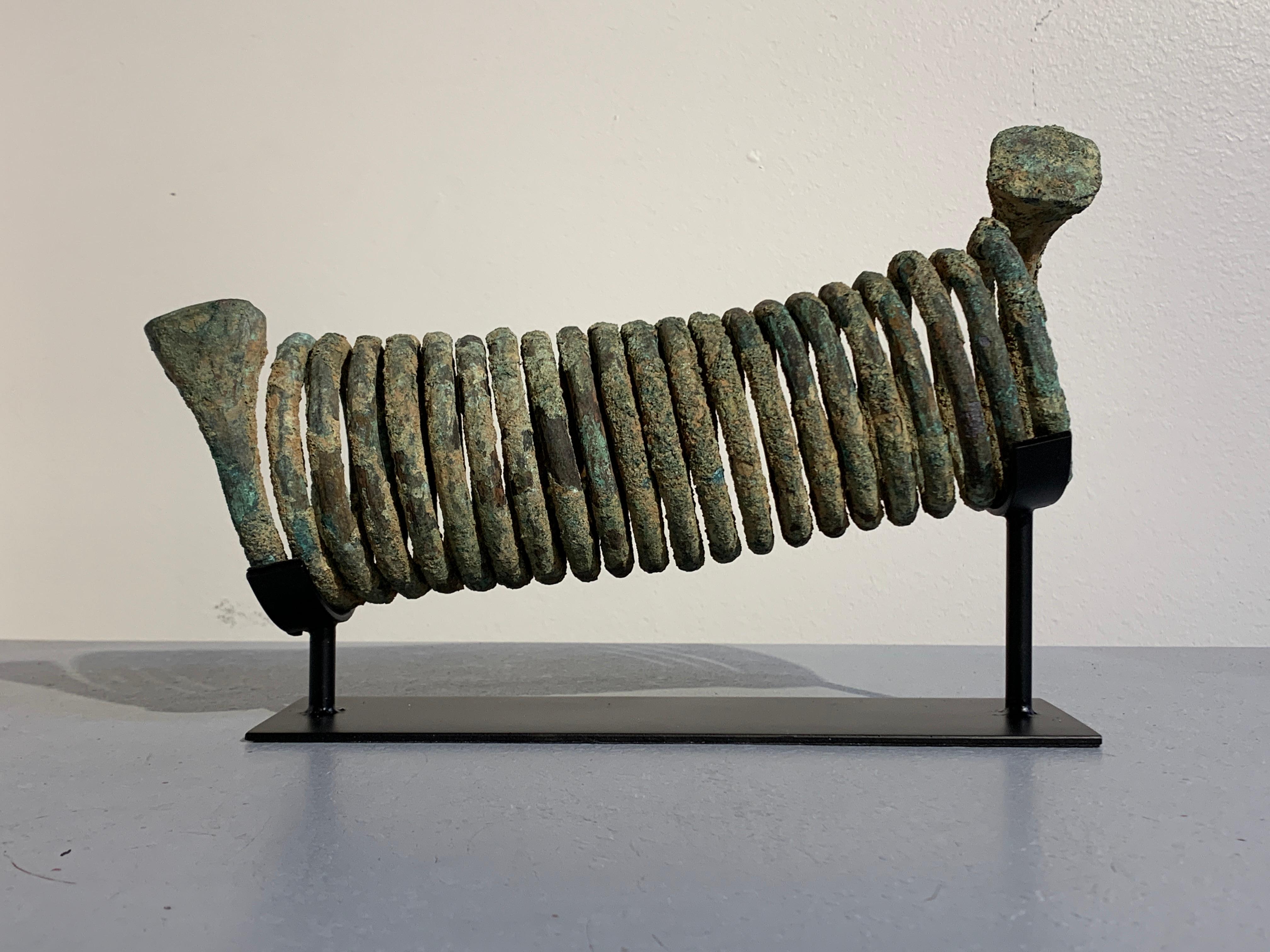 A large and attractive copper spiral manilla currency piece, Igbo tribe, Nigeria, early to mid-20th century.

The large currency piece formed as a coiled spring and comprised of twenty three coils terminating in bulging, squared off ends. The