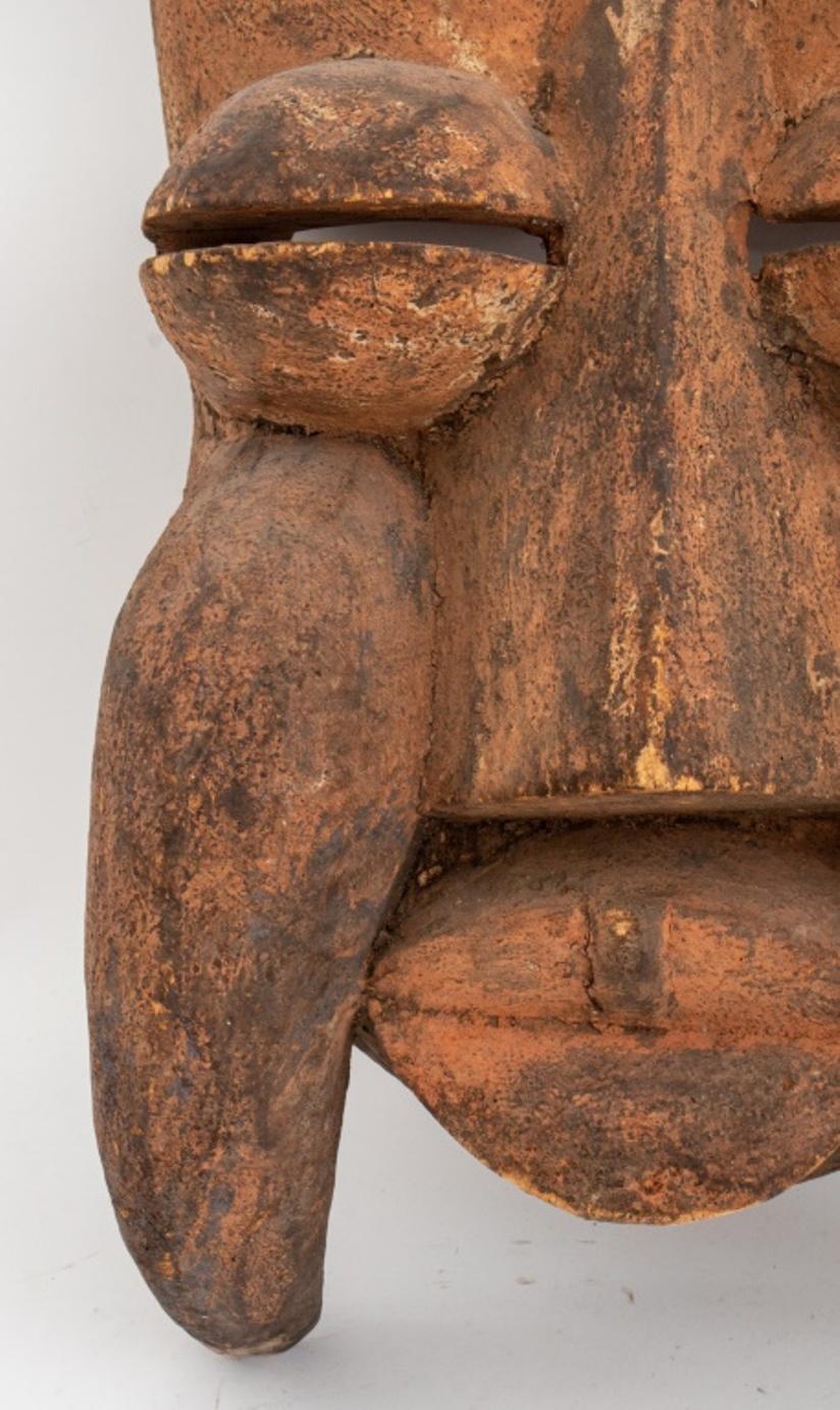 Masque africain, probablement de Côte d'Ivoire, début du 20e siècle ou plus tard, avec un visage abstrait de style géométrique semblable à celui d'un félin, avec des oreilles et des défenses pointues.

Dimensions : 26