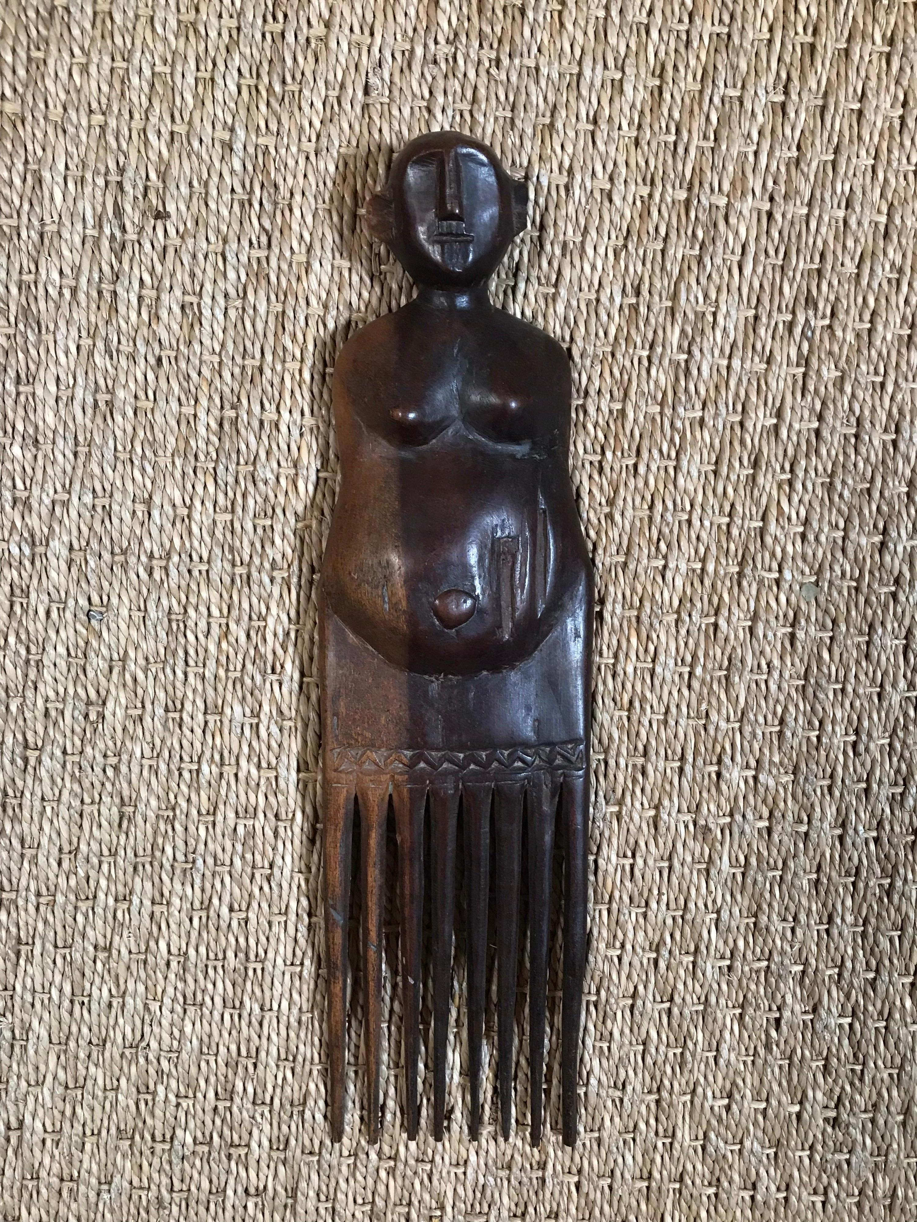 Ce peigne antique en bois est sculpté à la main en forme de figure humaine, les peignes faisant office de jambes. Il s'agit d'un fil métallique monté sur un support en acrylique. Il est de style Makonde et provient de la tribu Bantu du Zimbabwe.