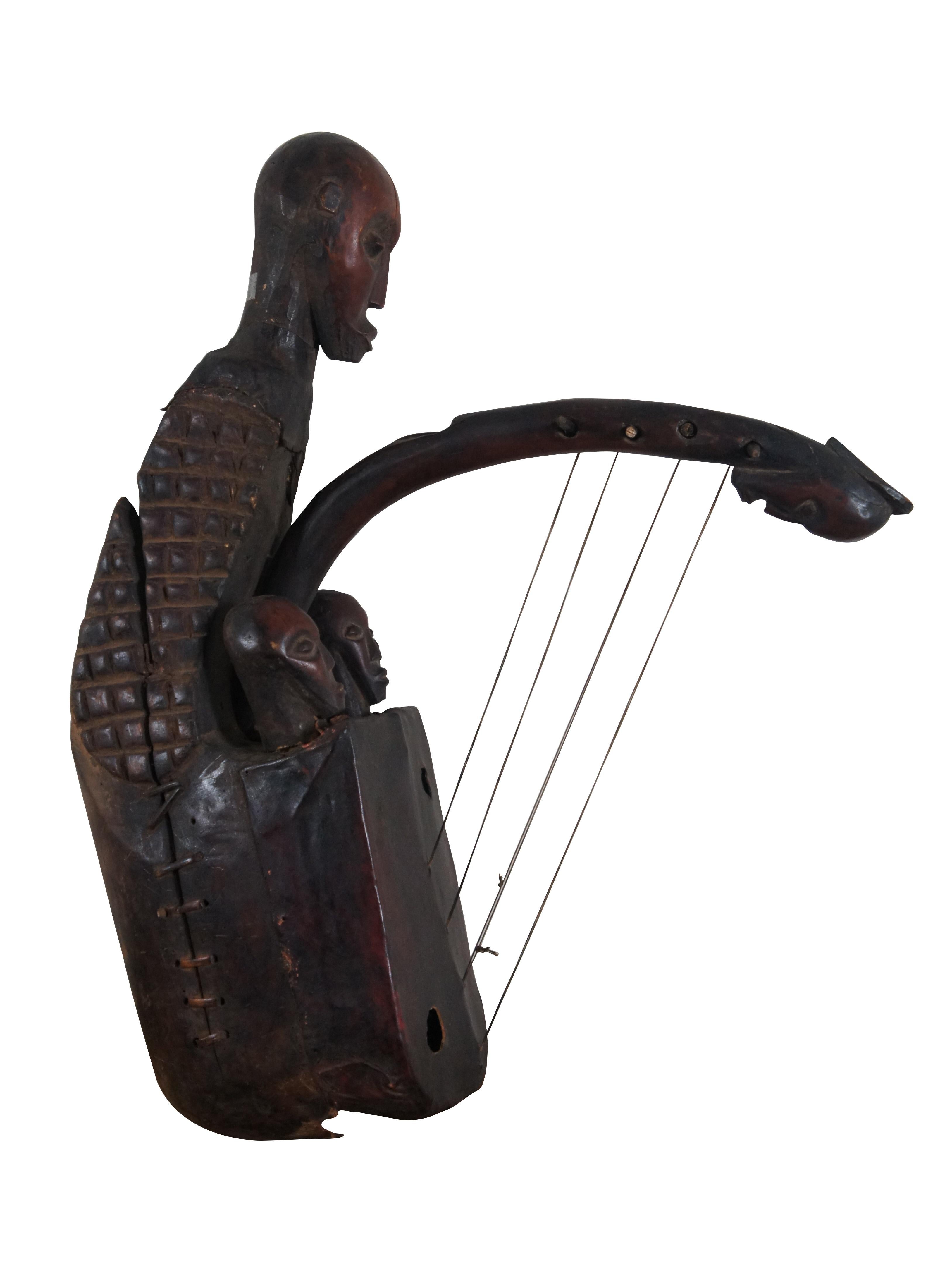 Rare vintage museum quality African Mangbetu fertility harp / domu, an African stringed instrument of the Mangbetu poeple, featuring a round wooden body, stretched red leather head with two sounding holes and four strings on pegs. Hand carved, in