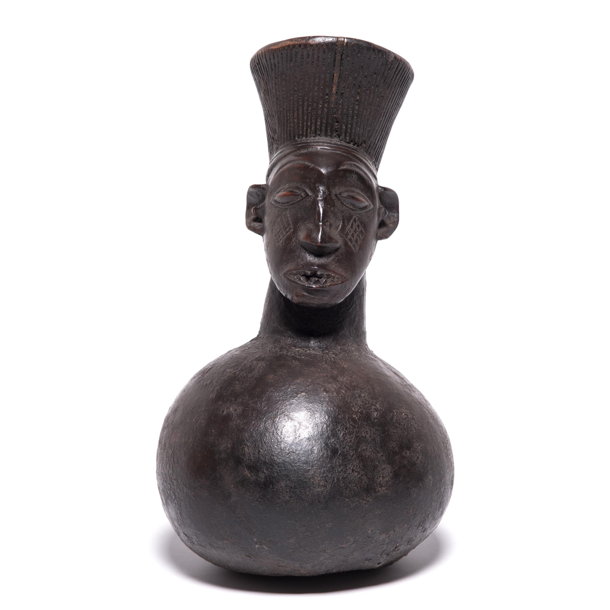 The Mangbetu people focused on highly realistic art forms. From the spout formed to look like hair, through the face, and down to the gourd shaped base, this jug seamlessly transitions between forms, marking it as a master work. The face depicts an