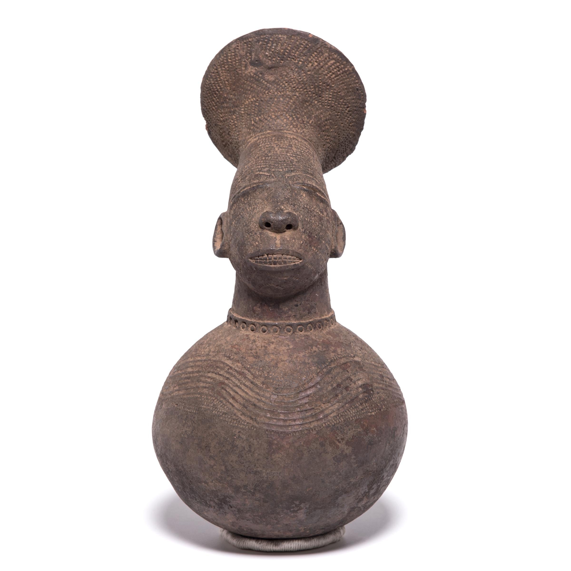 The Mangbetu people focused on highly realistic art forms. Two aspects of the tribe's traditional culture can be seen in this handled jug—the allusion to tall coiffured hair, and the tribal ritual of elongating heads during growth. This water jug