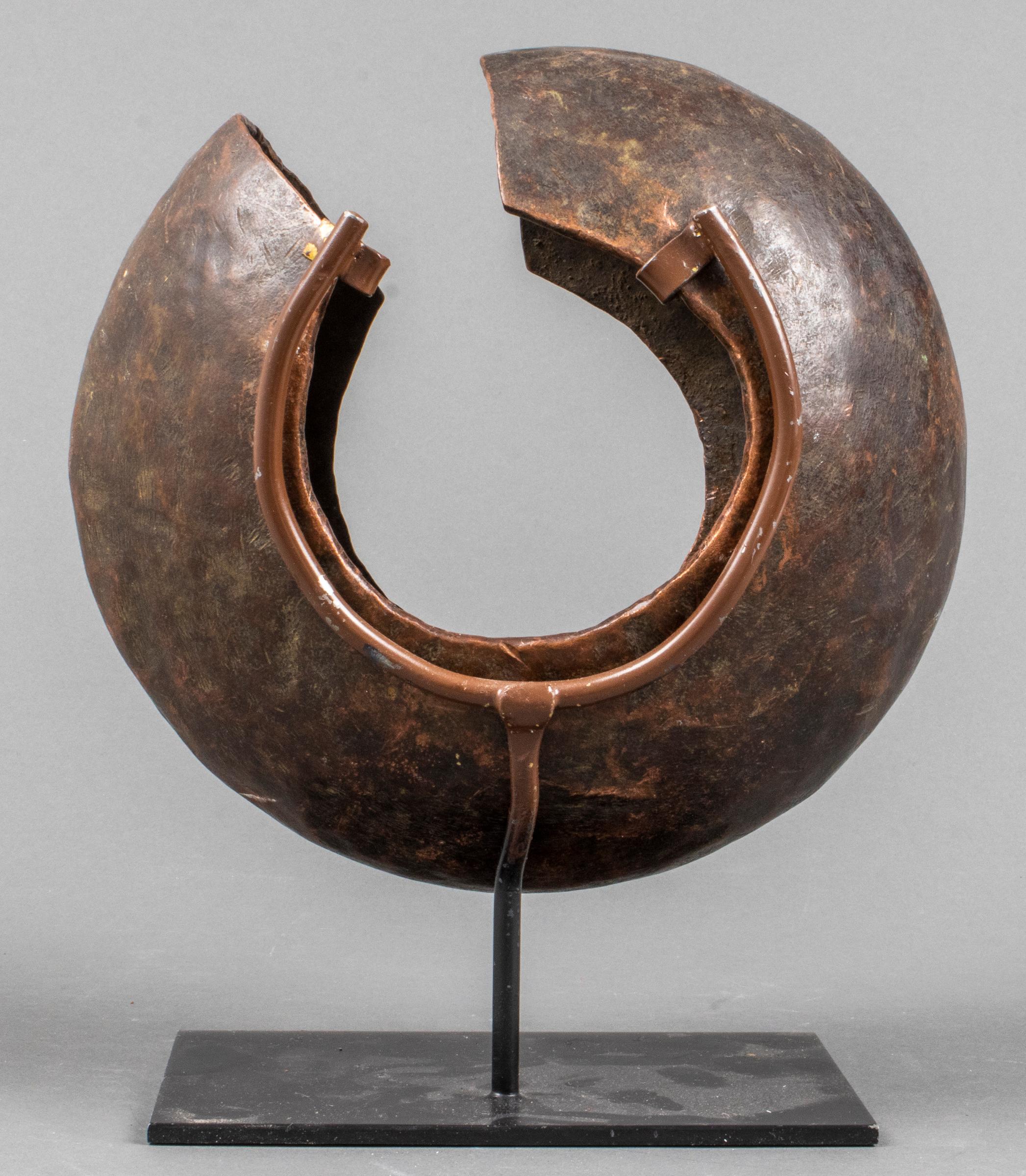 African Mbole People (Democratic Republic of the Congo) copper currency anklet ring, spherical in form with open side, raised on metal stand. Overall: 10.75