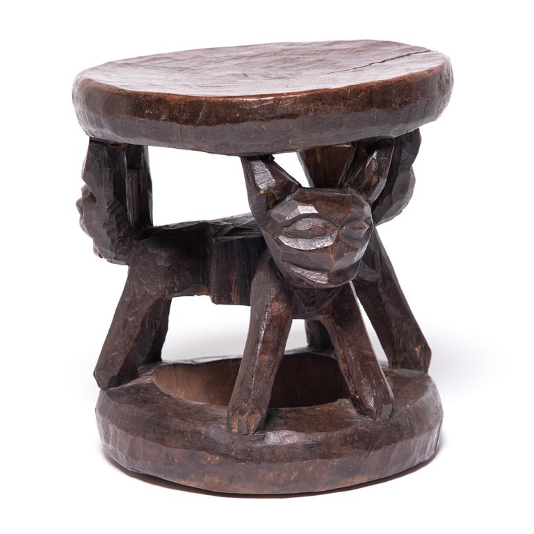 Marked by the telltale Bamileke rounded disc seat and base, this stool is supported by the linked forms of three animalistic figures. Created from a single tree trunk, the stool serves dual purposes as both a seat and a wonderfully sculptural