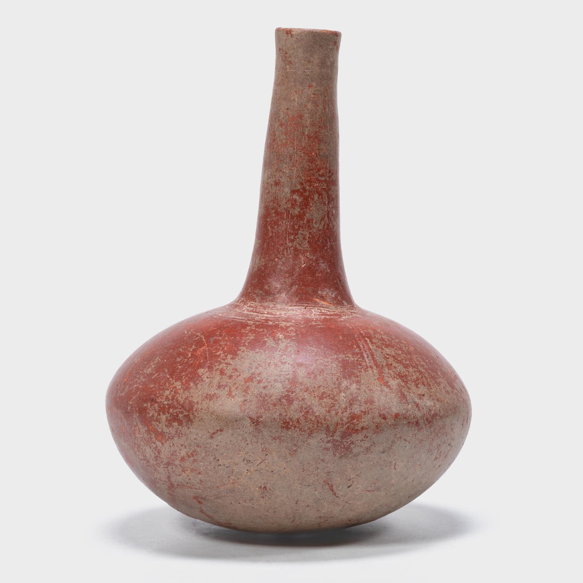 Ricoperto da una splendida barbottina di argilla rossa, questo vaso africano modellato a mano ha una silhouette drammatica con un corpo tozzo e ovoidale e un collo lungo e stretto. Un motivo a tratteggio sottilmente inciso circonda la base del lungo