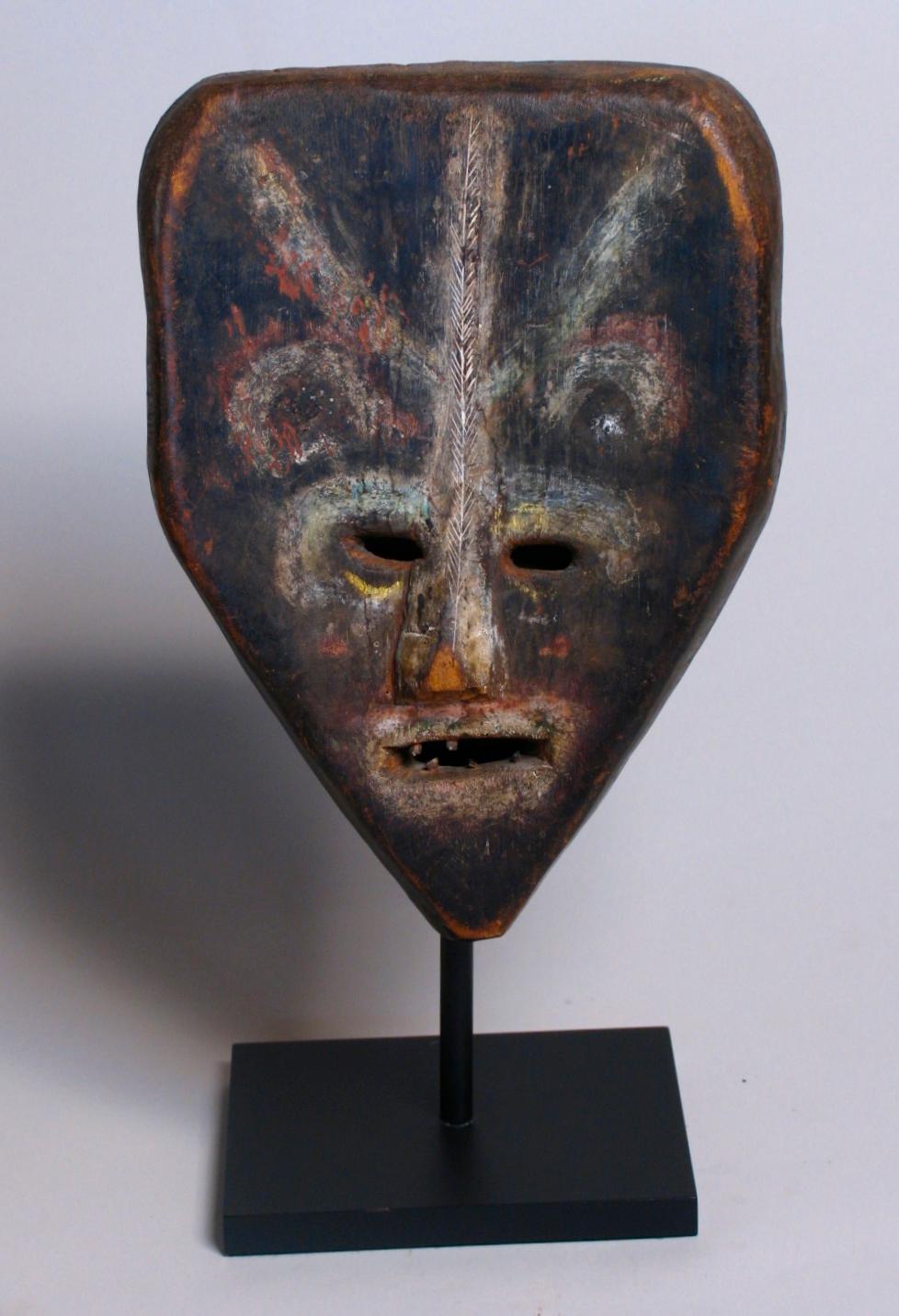 An unusual African ritual mask, Ubangi river basin, carved from a single piece of a close grained soft wood, the overall form with a squared forehead with rounded corners, changing at the brow line into a triangular form with a pointed chin, the