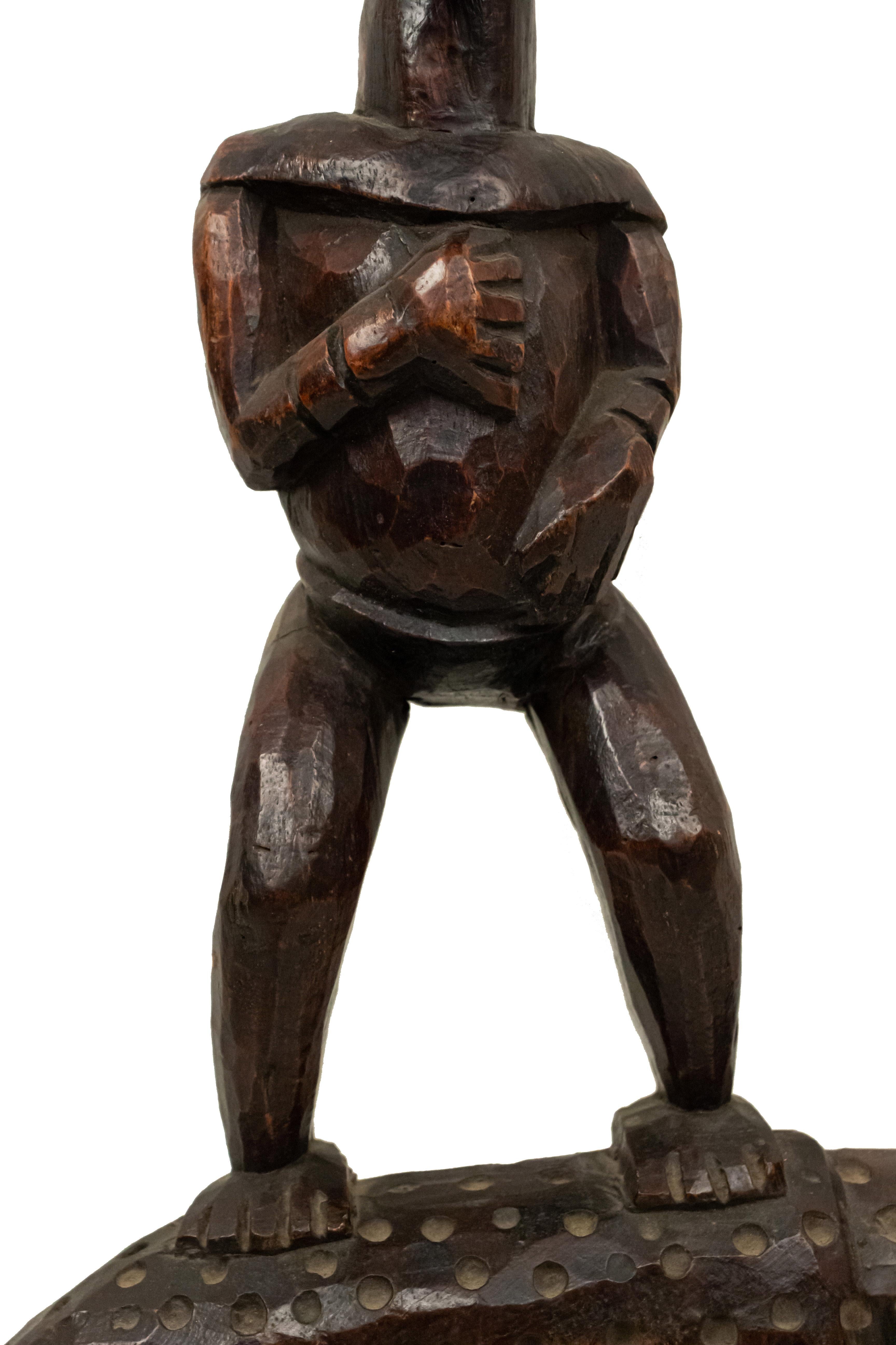 Wooden African sculpture of a human figure standing on the back of a leopard.
 
