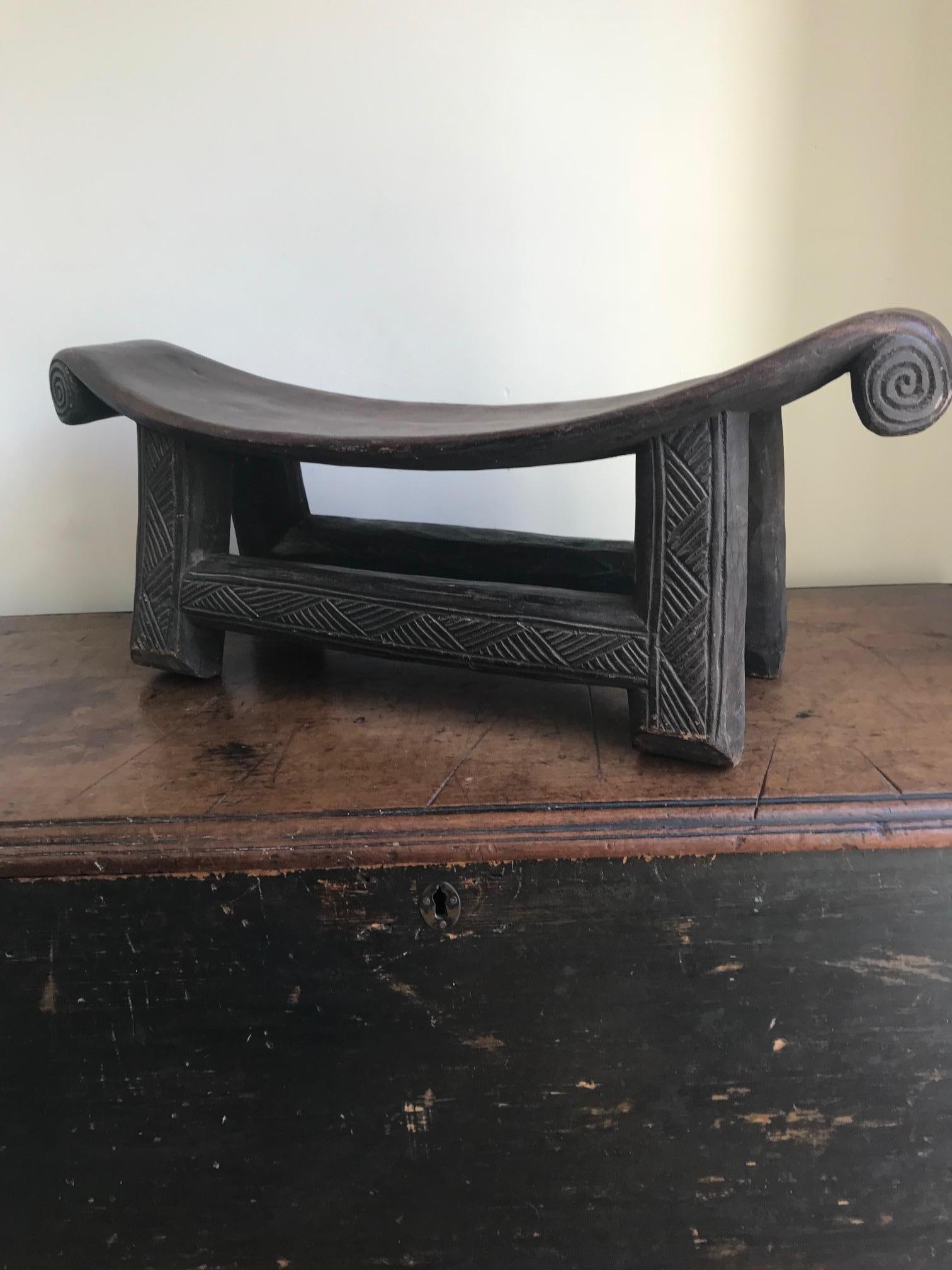 An elegant wooden tribal stool most probably originating from the Shona Tribe Zimbabwe, due to its linear carvings and scrolled circular details.