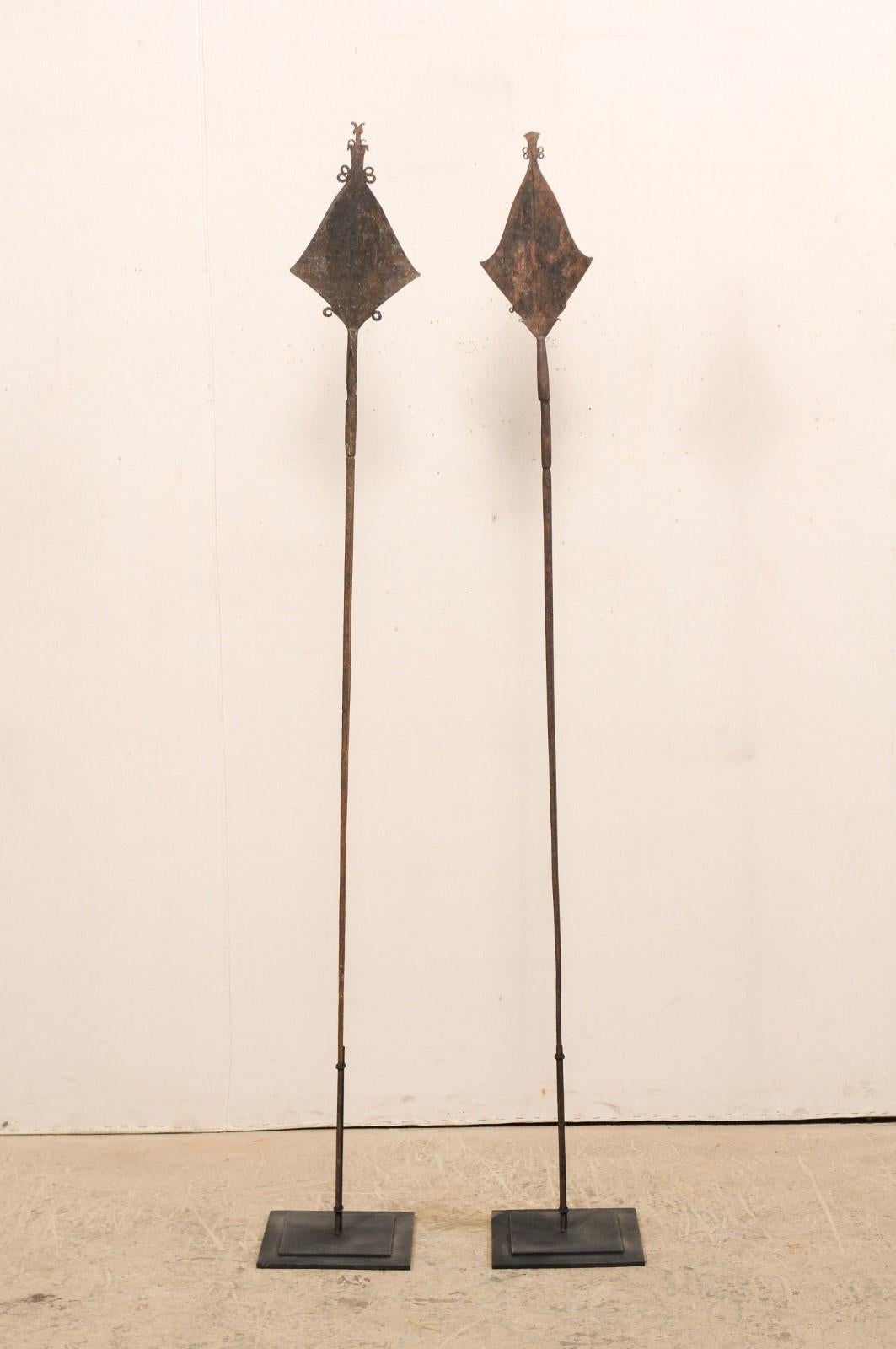 This is a pair of vintage African spear currencies from the Mbole peoples, Democratic Republic of Congo which are nicely presented upon custom metal stands. These African currencies take their name from their spear-shaped tip design, though due to