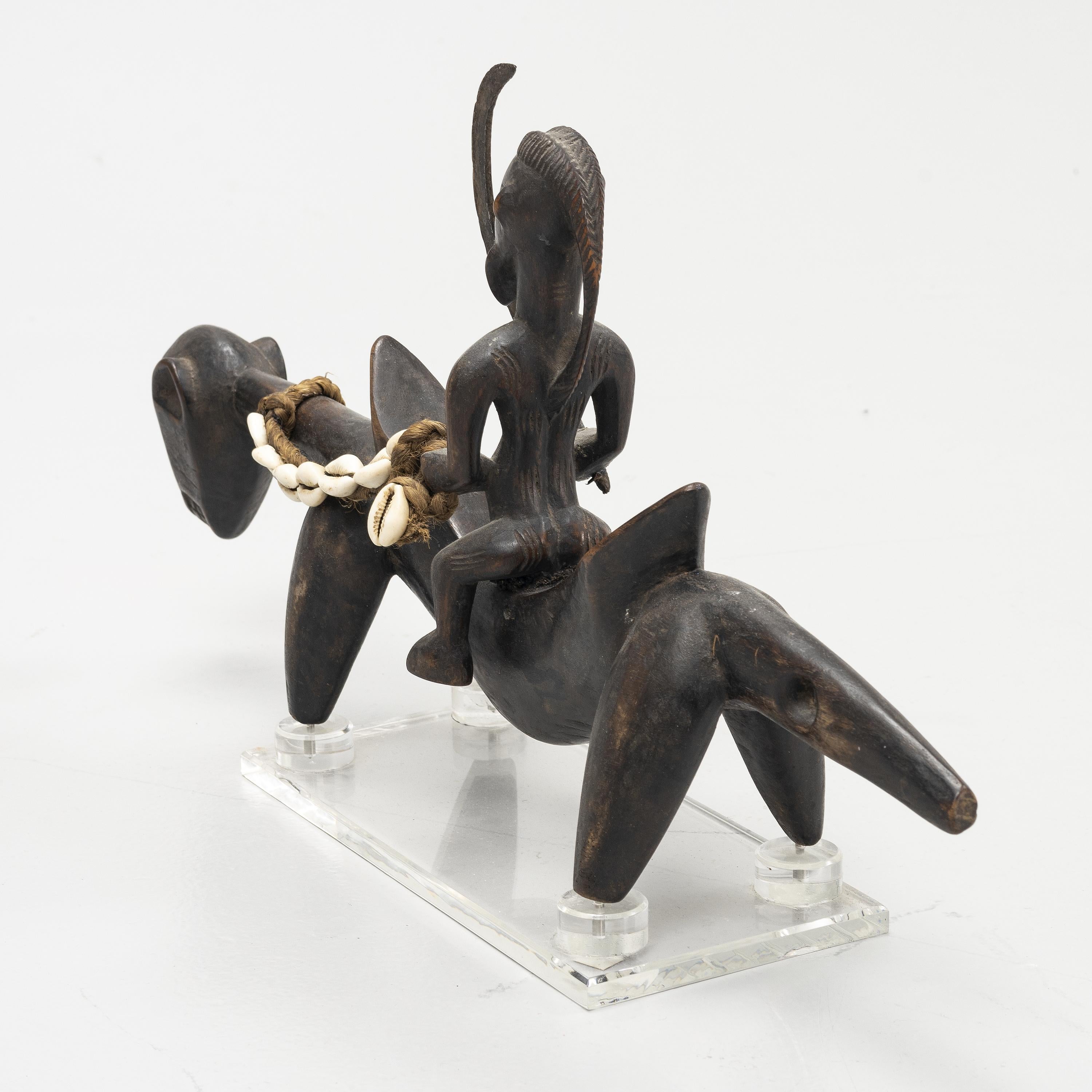 Statue d'un cavalier sur sa monture parmi la tribu des Senufo installée dans le nord de la Côte d'Ivoire. Sculptée dans un bois dense. Belle patine. La statue est dotée d'une base en acrylique fabriquée sur mesure.
Provenance : Collection privée