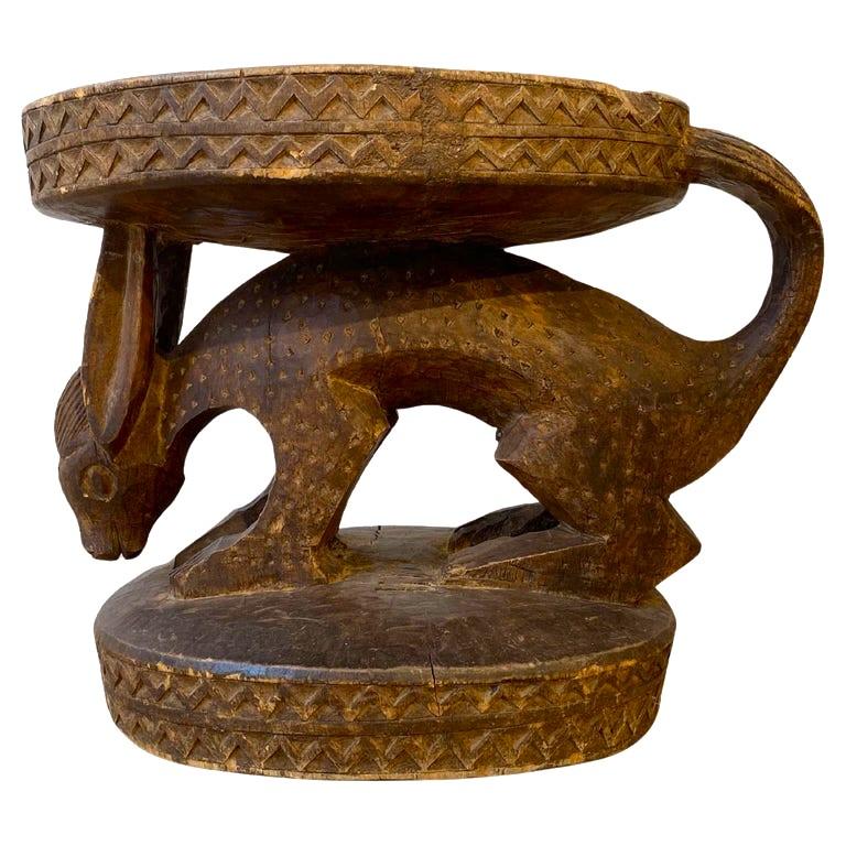 Afrikanischer Hocker mit Karyatide aus Kamerun, Bamoun oder Bamileke, wohl um 1920, Holz geschnitzt und dunkel patiniert, ovale, mit geometrischen Kerben verzierte Sitzfläche, Stütze in Form eines geschnitzten Tieres (Fabelwesen, inspiriert vom