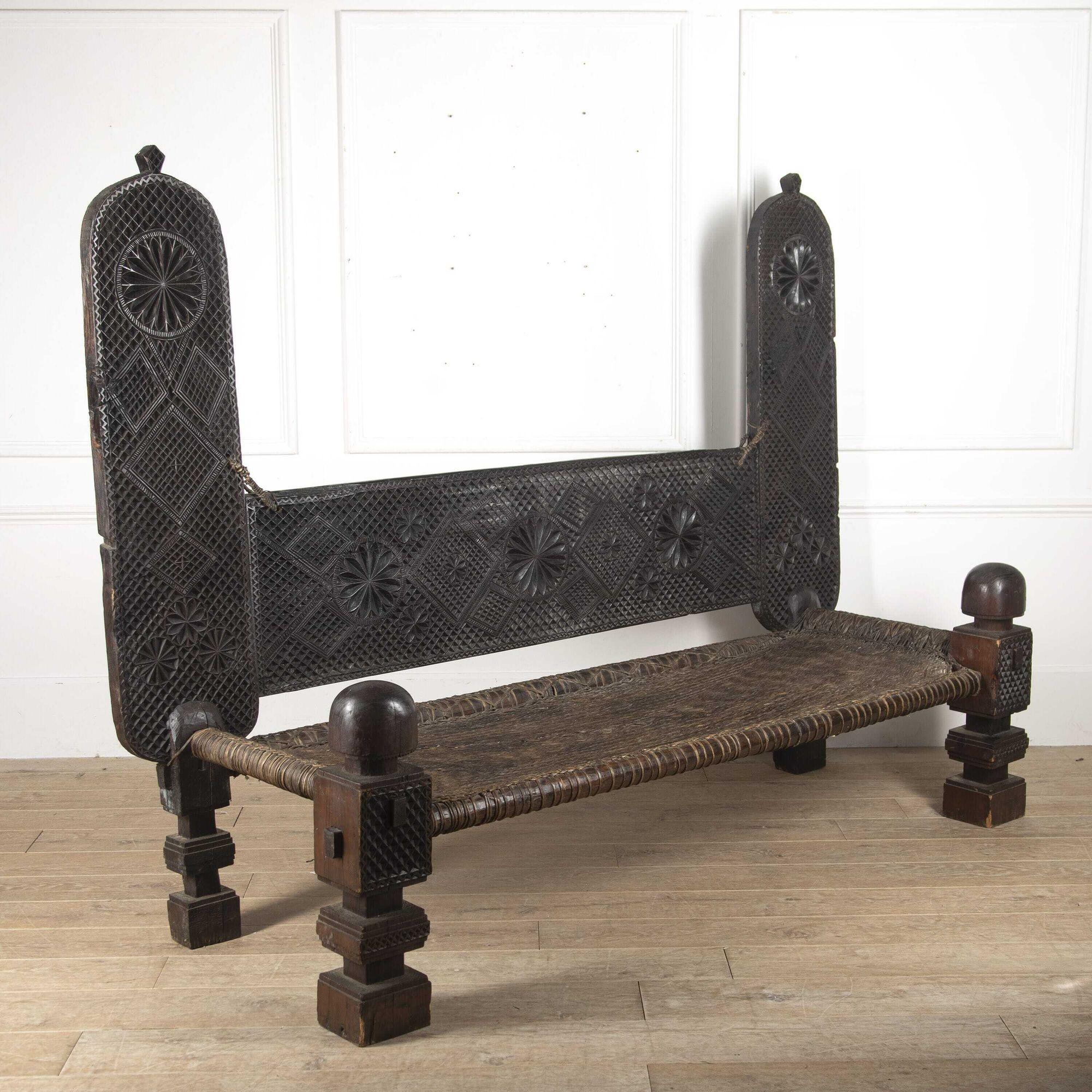 Impressive oversized daybed originating from the East African Swahili coast.
This unusual daybed is constructed of geometrically carved panels and oversized legs, that are held together by strips of animal hide, bound, and woven to form the bed