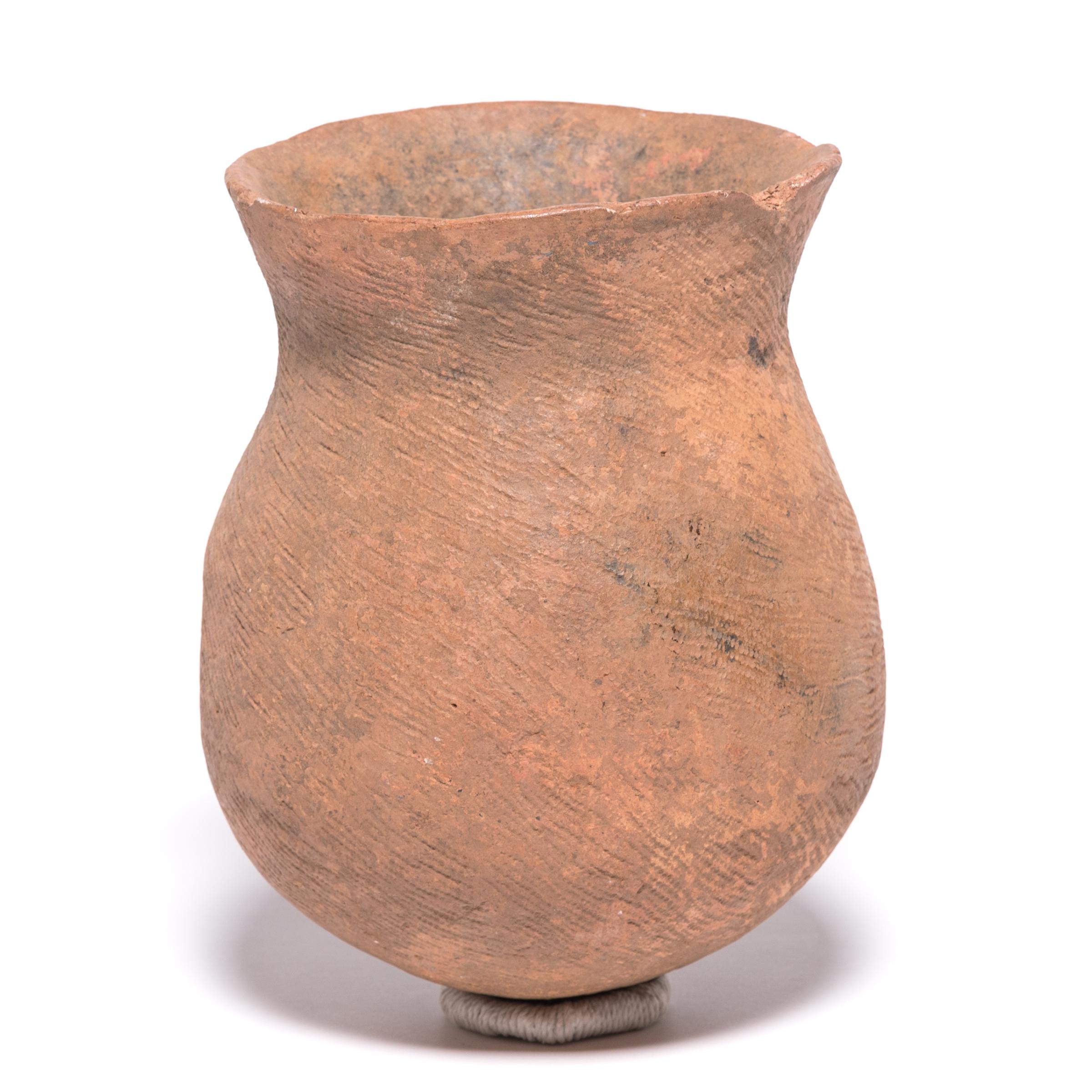In spite of terracotta's naturally earthy and solid presence, this tribal storage vessel has a fantastic sense of movement. The hand incised scarifications swirl through the solid ceramic, pulling the eye from the base of the vessel in a smooth