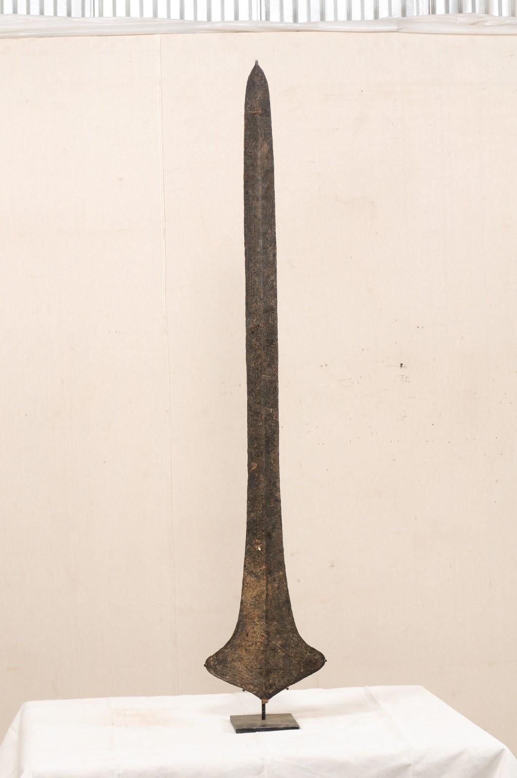 An African iron currency blade or sword currency from the Nkutshu, Topoke & Songo Meno peoples, Democratic Republic of Congo (Zaire) which is nicely presented upon a custom metal stand. Such blades were used by various tribal groups in the