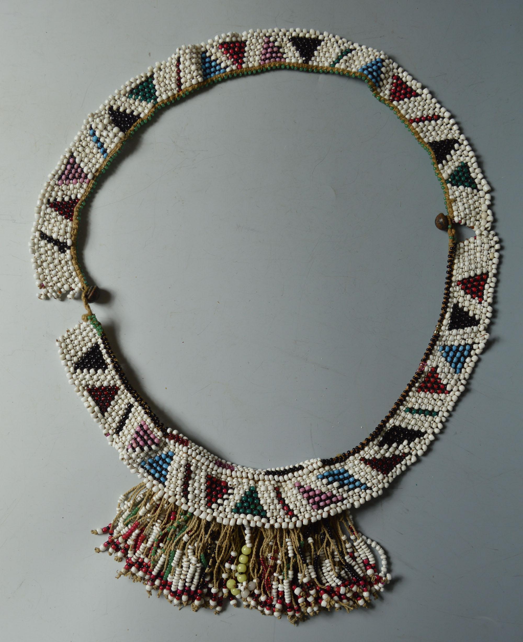 African tribal antique Zulu bead work apron belt South Africa
A fine old Zulu bead work apron belt with central fringed section
the belt in 2 sections with metal buttons glass beads beaded in a triangular pattern
Period early 20th century.

