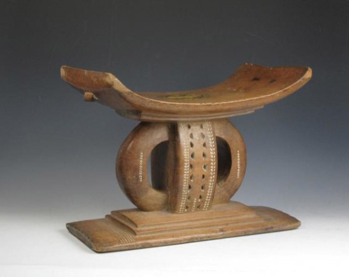 A fine old Ashanti Chiefs stool with Royal Insignia.
A very fine quality stool from a provincial Chiefs residence.
Carved from a single piece of wood stepped base with double interlocking circular design pierced with geometric patterns
and Royal