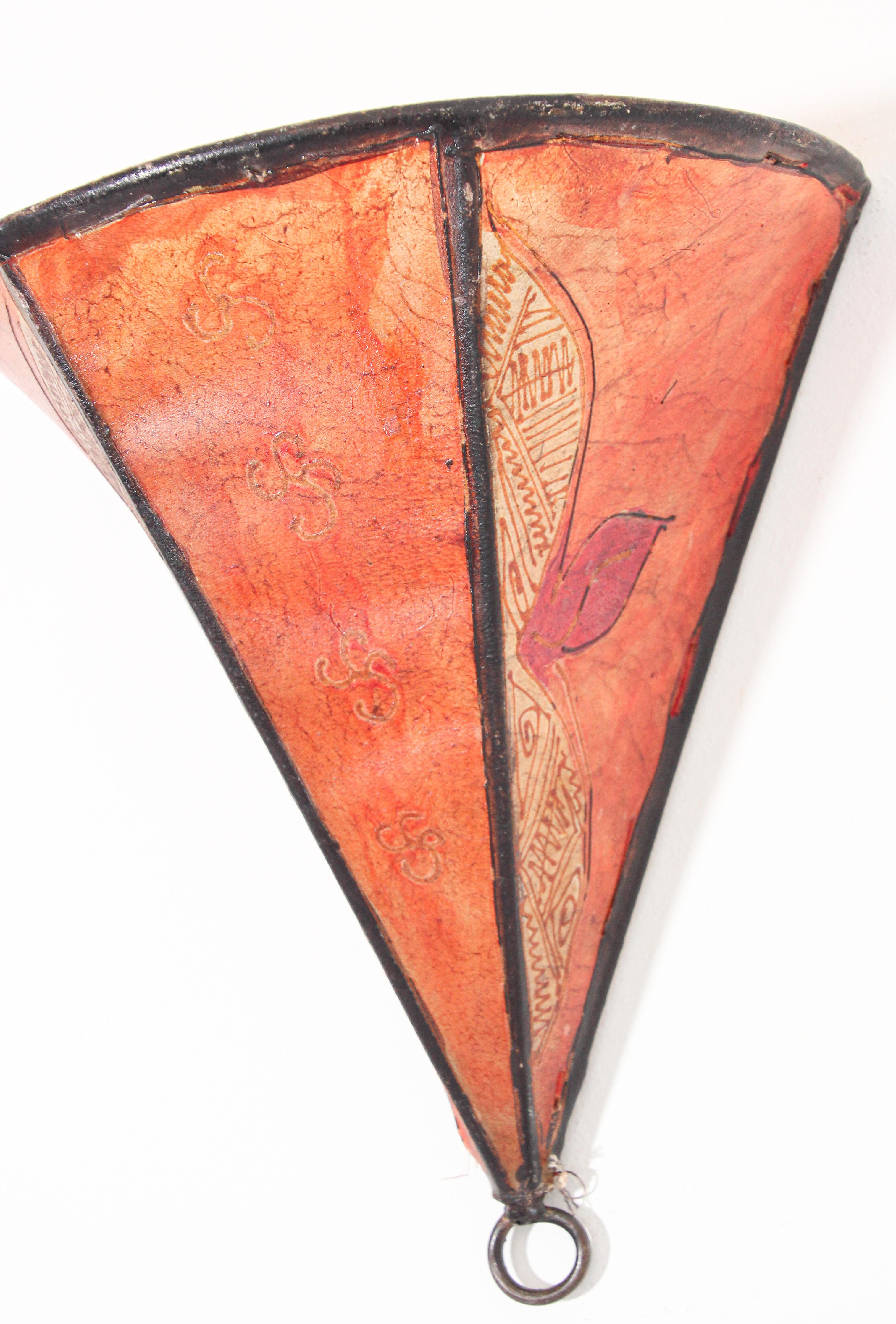 African tribal art parchment wall shade sconce featuring a large triangle hide form stitched on iron and hand painted surface.
These Moroccan art pieces could be used as wall lamp shade.
Iron frame covered with hide parchment which has been hand