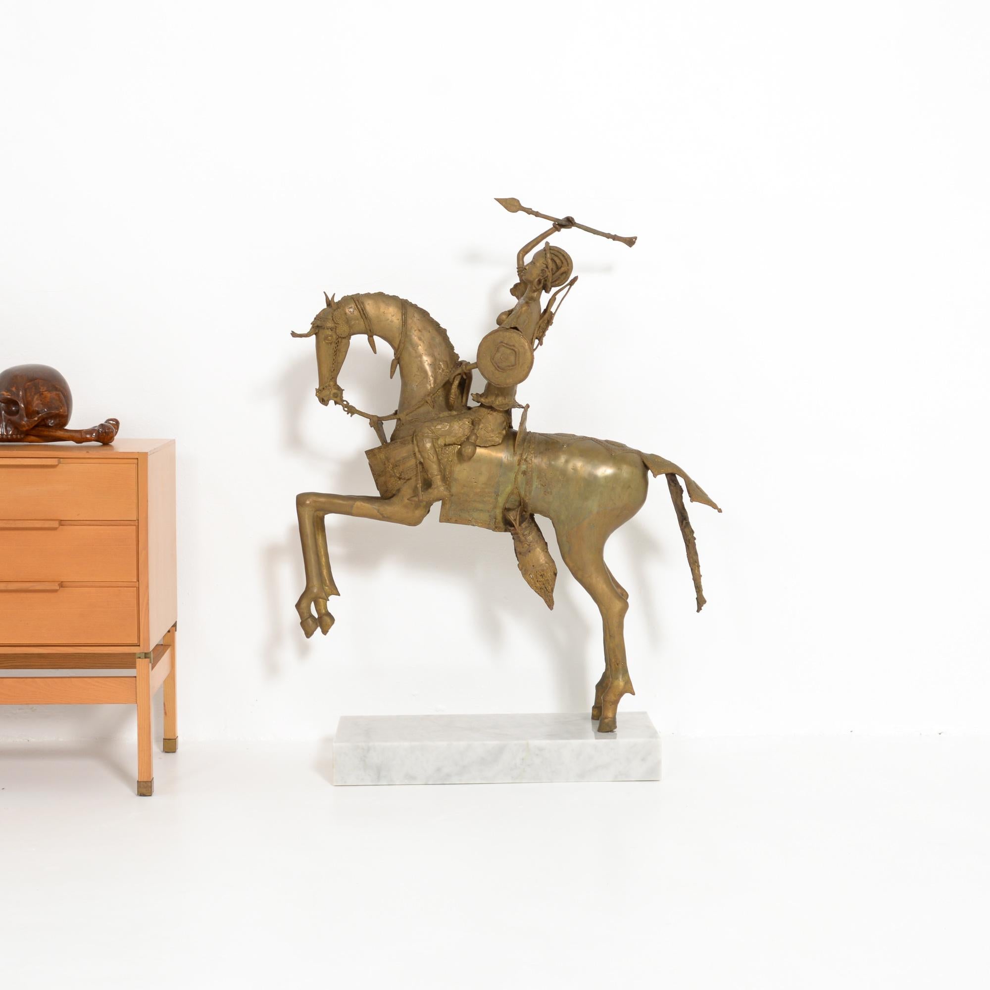 Cette grande sculpture africaine en bronze représente une cavalière sur un cheval. C'est une sculpture expressive et brutaliste en pleine action. La femme guerrière a une lance prête à l'emploi et le cheval se cabre.
Les chevaux et les cavaliers
