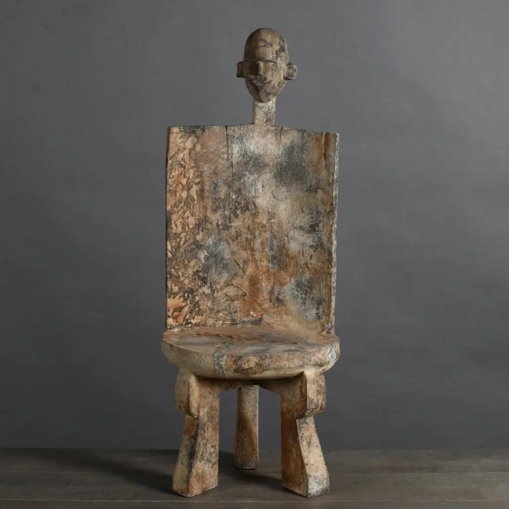 This African tribal stool in patinated wood is a striking piece that immediately captures attention with its primitive style and unique aesthetic. Inspired by a traditional model from the Zomoro tribe in Tanzania, this stool is a faithful