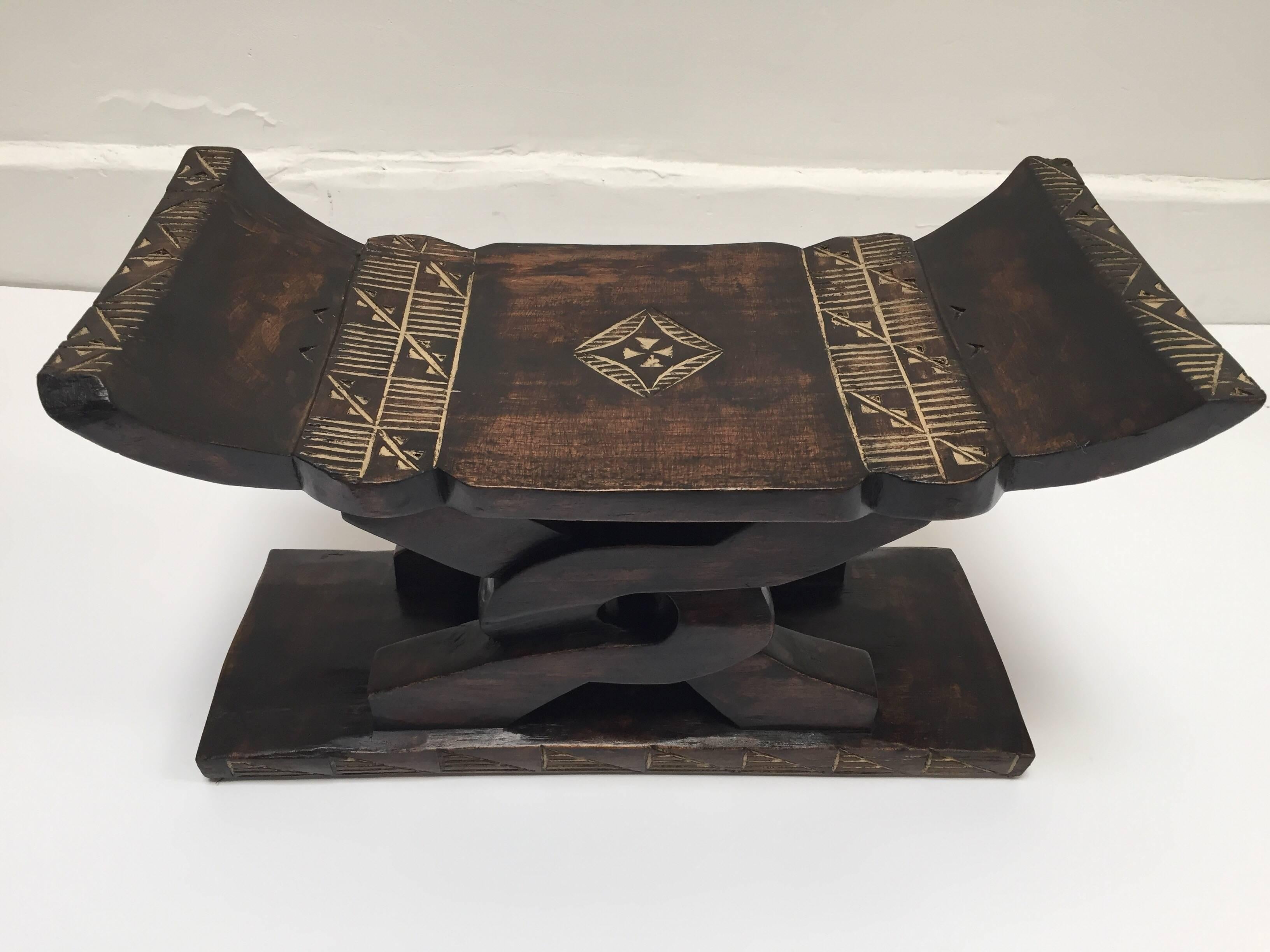 African handcrafted stool with geometric designs. 
Hand-carved African wood with a curved seat raised on a carved wooden support with a slim plinth base. 
Africa, Ghana, circa 1980.
Could be used as a side table or stool.